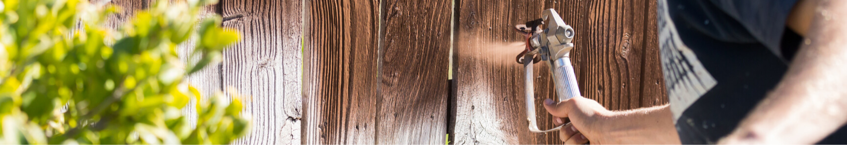 A wooden fence being stained to perfection.