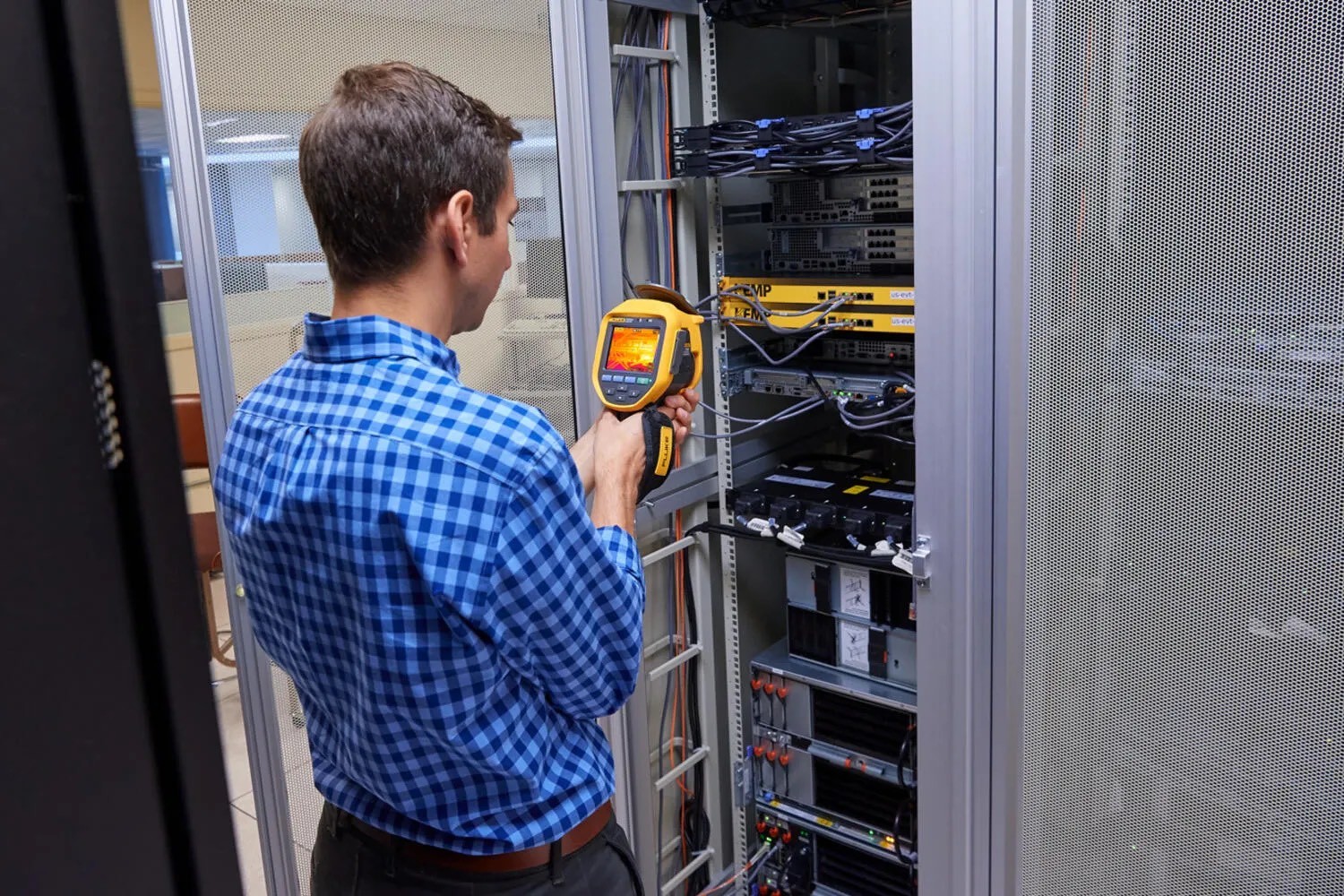 Technician scanning a server rack with a handheld infrared camera