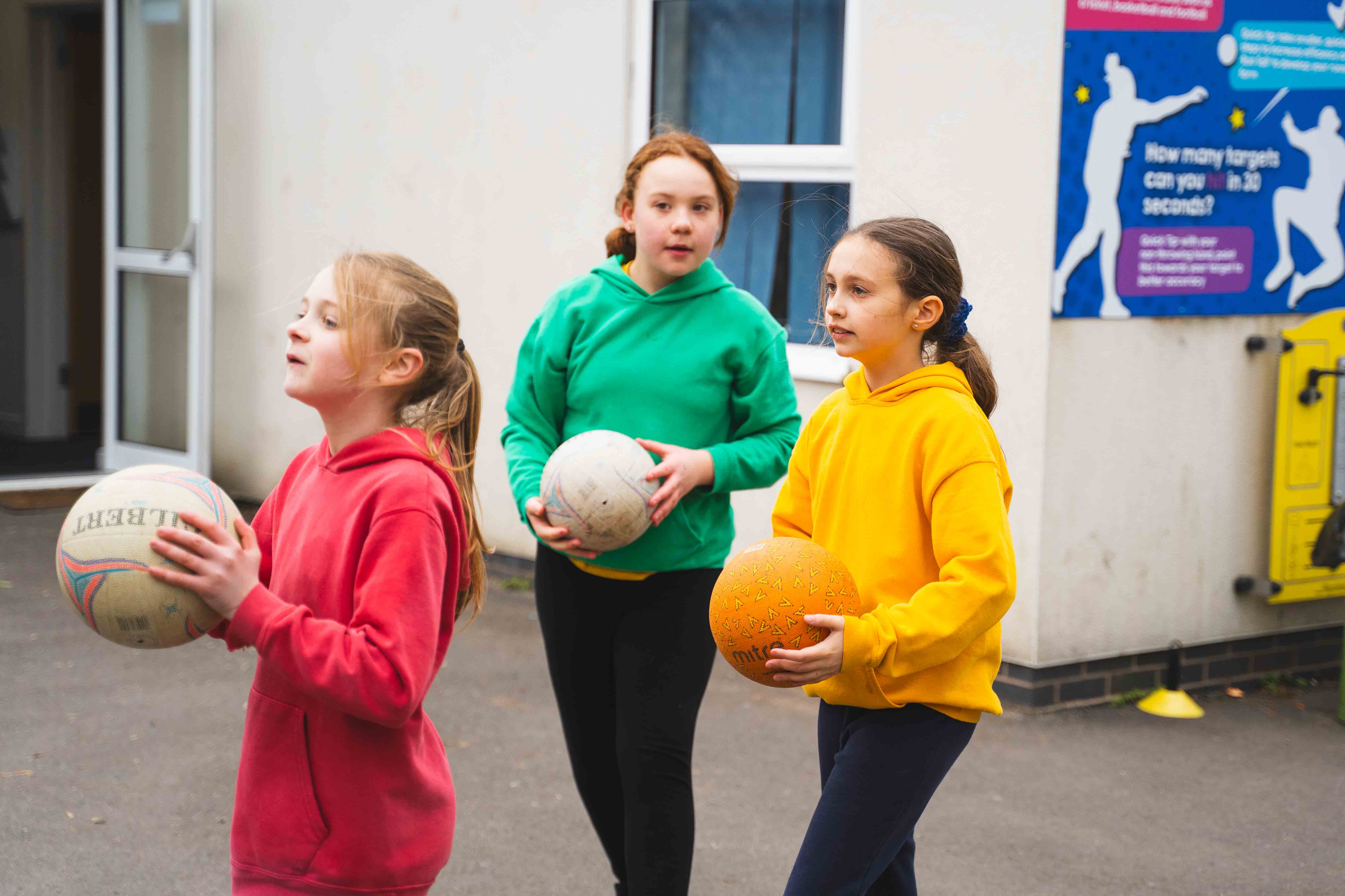 A group of girls holding Netballs in Delta's netball coaching.
