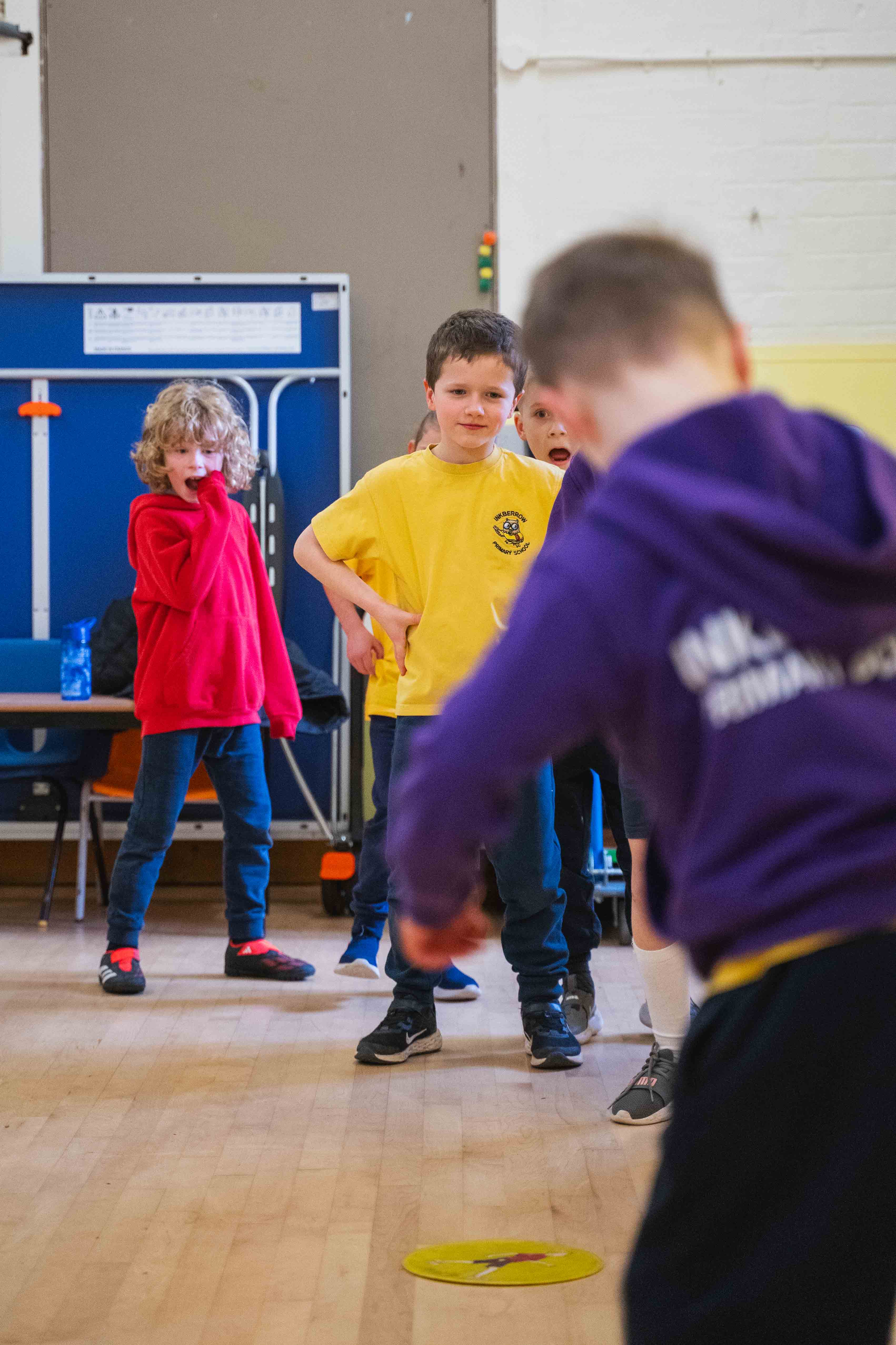 Primary school kids Children enjoying  a fun group  sports club session inside a sports hall.