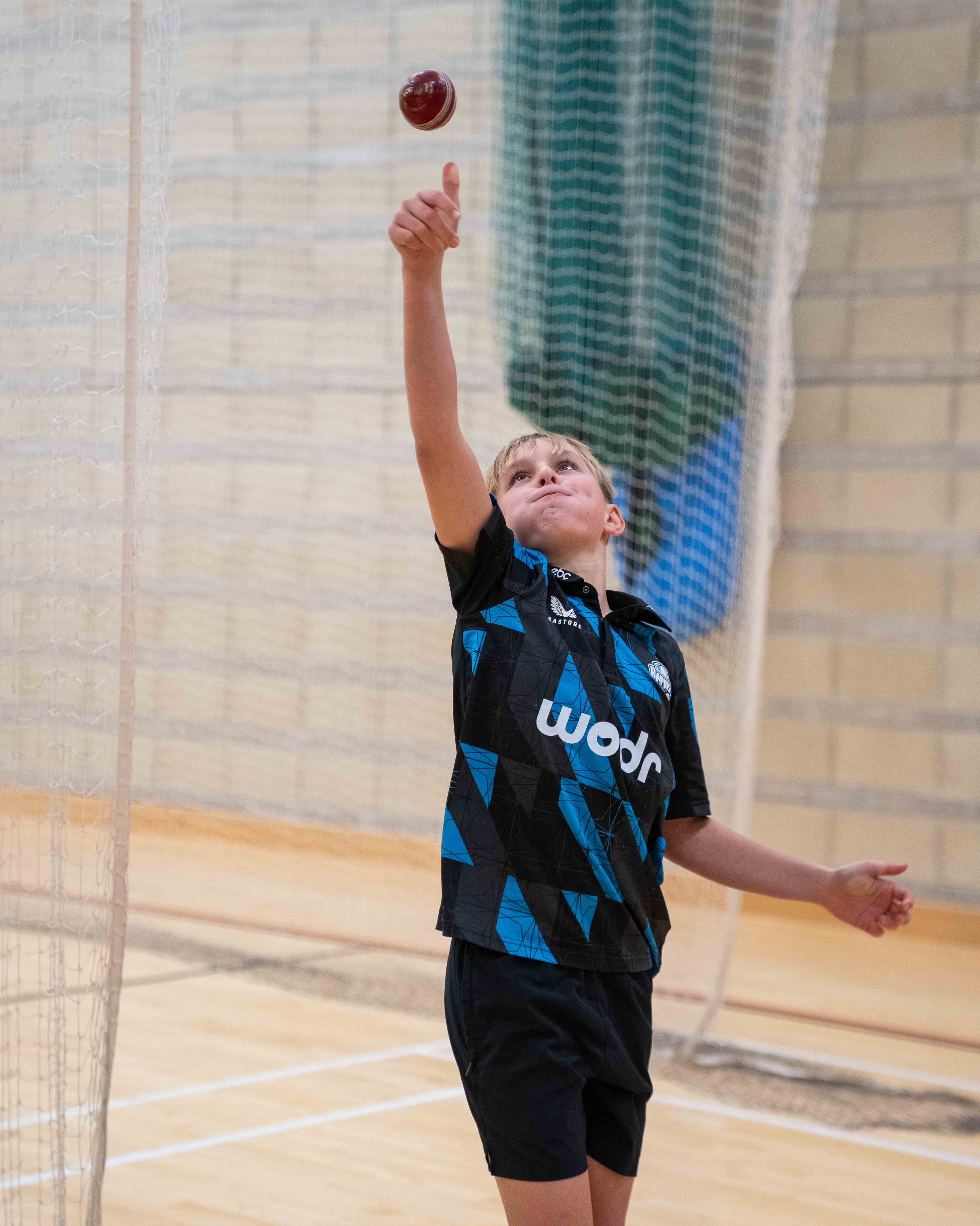 Boy throwing cricket ball in the air