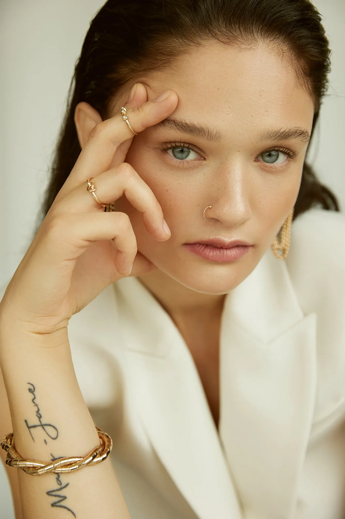 Eine Frau mit roten Haaren sitzt auf einem weißen Boden und laechelt in die Kamera