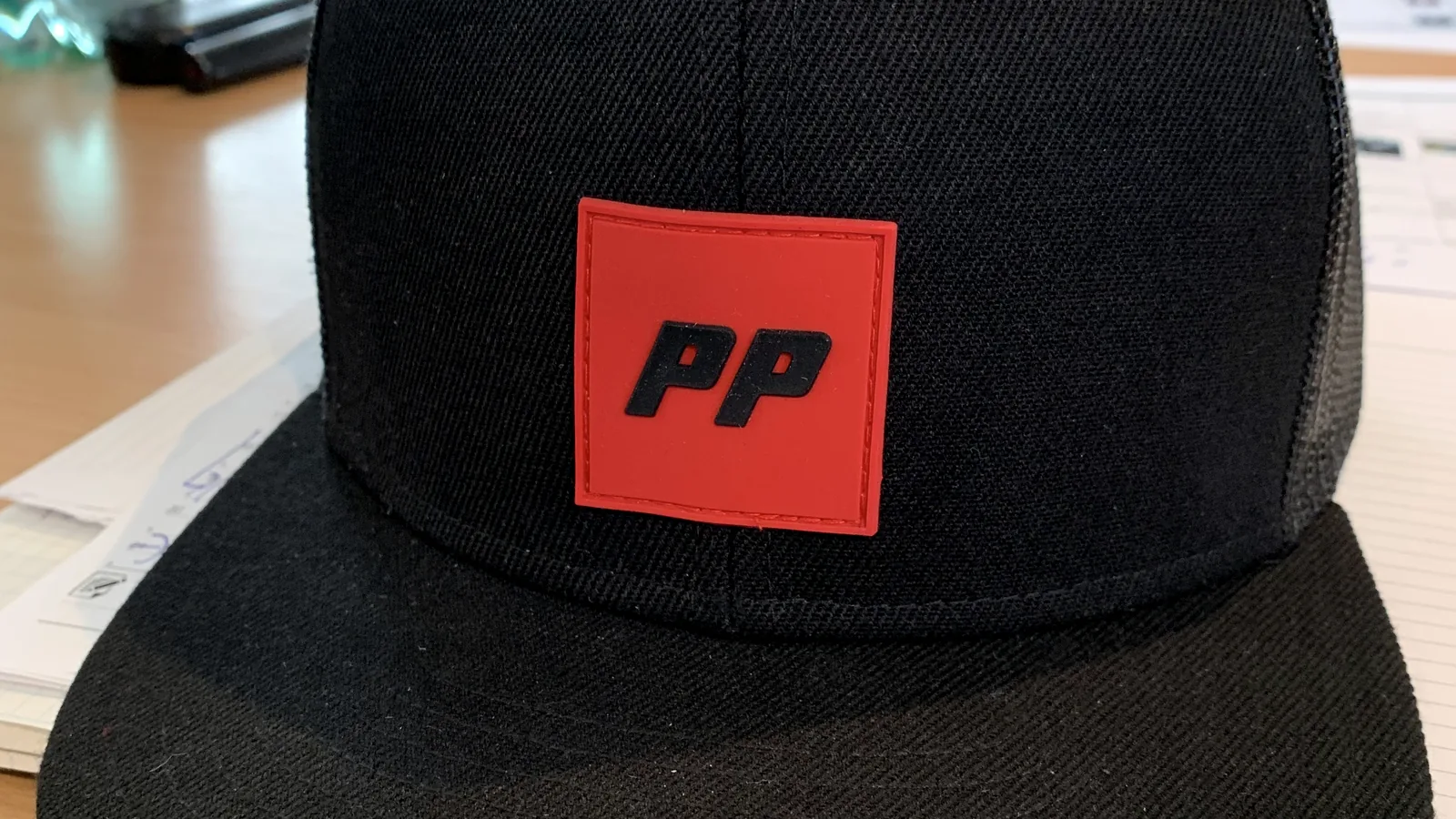 Schwarze Cap mit rotem Logo-Patch als Beispiel für eine durchgezogene Markenlinie