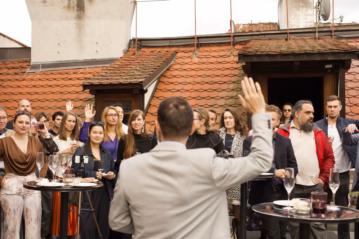 David Papa asking the audience a question during his talk on humor and leadership at Impact Night Summer Edition on a Prague rooftop