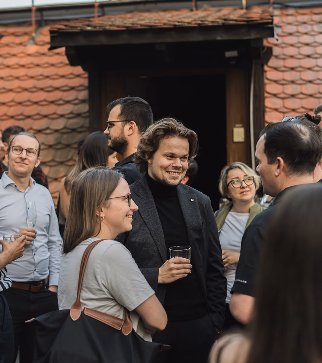 Guests chatting with drinks on a Prague rooftop at Impact Night with Barbora Werdmölder