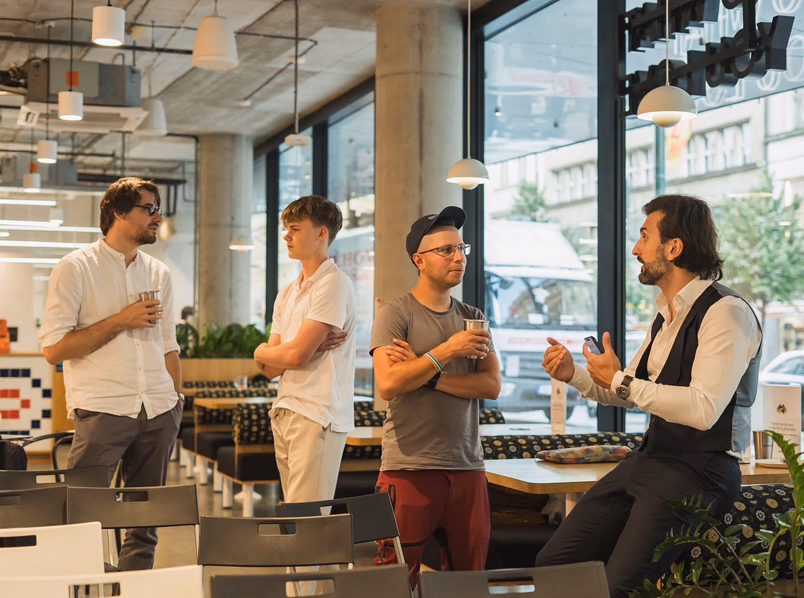 Four guests with drinks networking in a bright café at Impact Night with Jana Sedláková