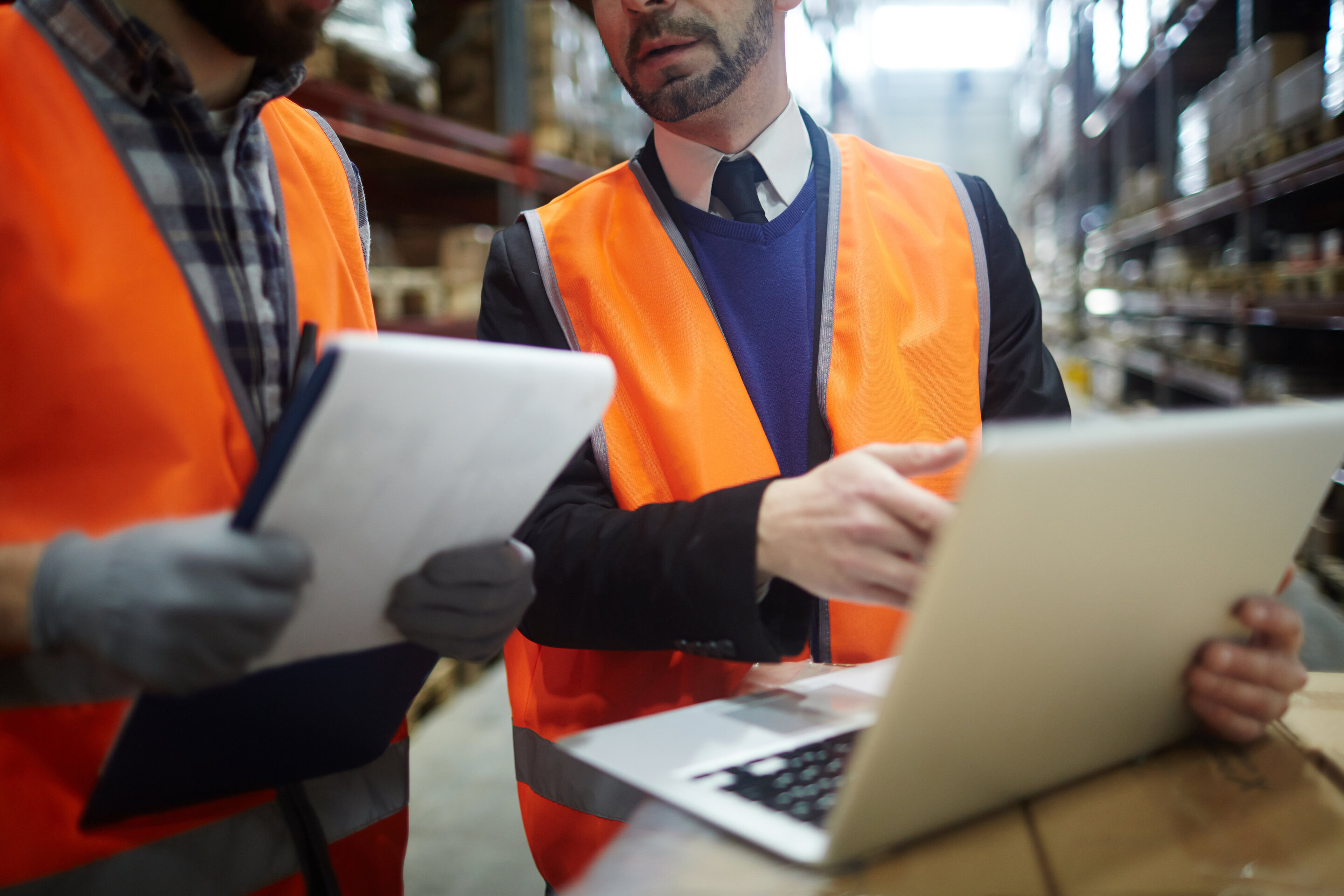 Image of maintenance employees looking at the MaintainX application on on a laptop in a warehouse setting