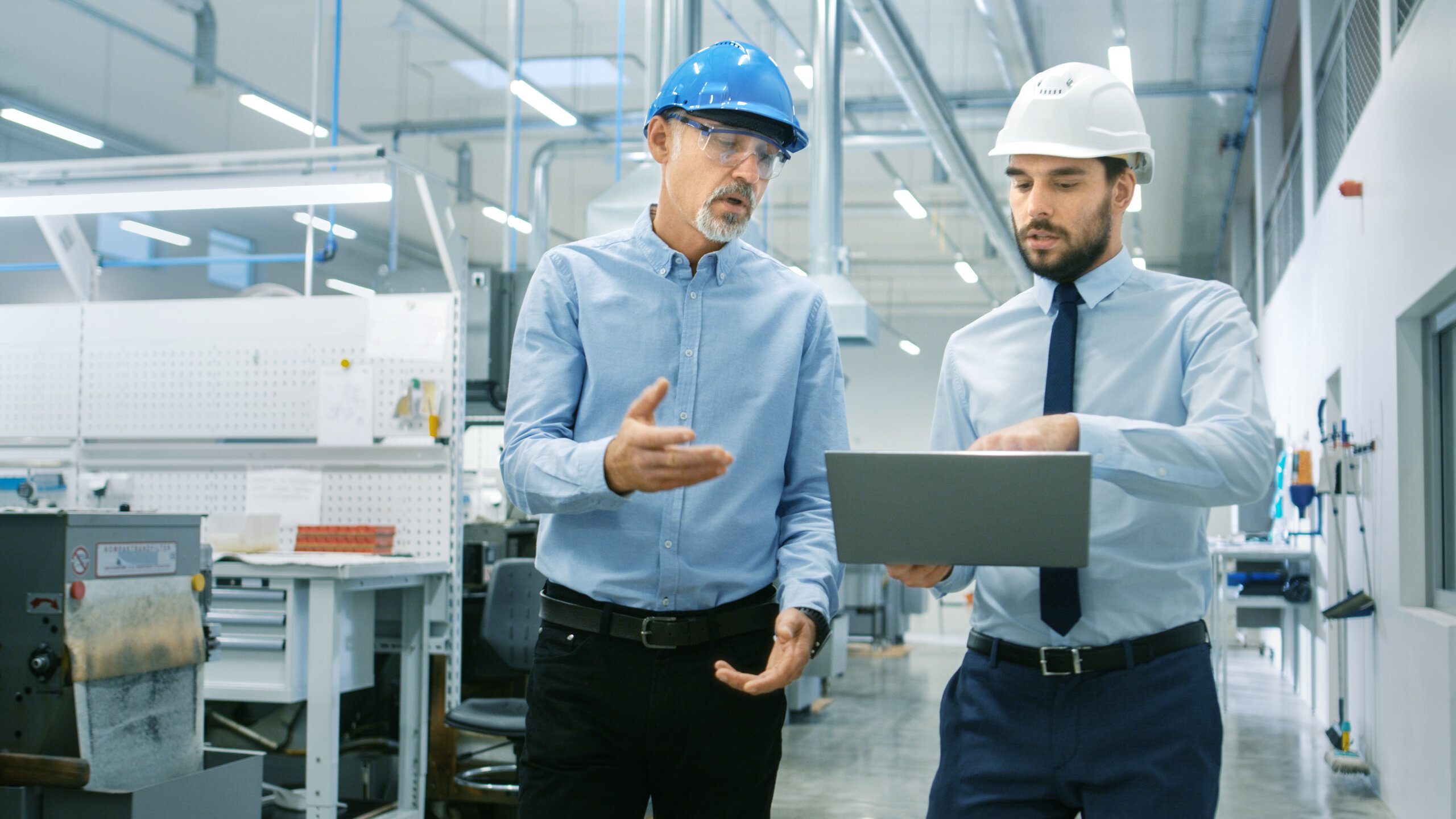 Image of maintenance employees looking at the MaintainX application on on a laptop in a warehouse setting