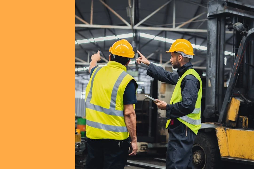 Two maintenance engineers inspect machinery. One is holding a tablet mobile device.