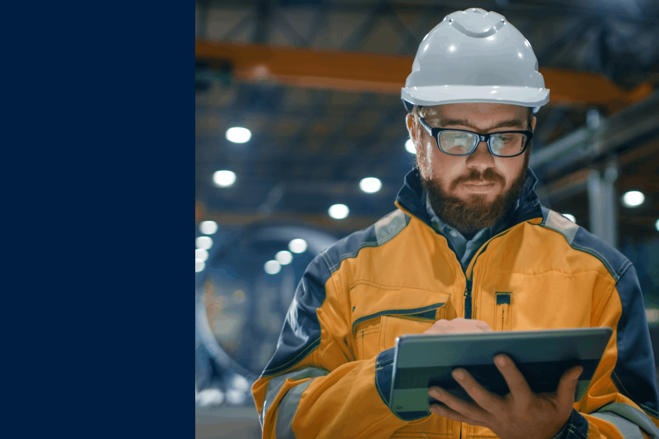 man in hardhat working in a factory while looking at a mobile device