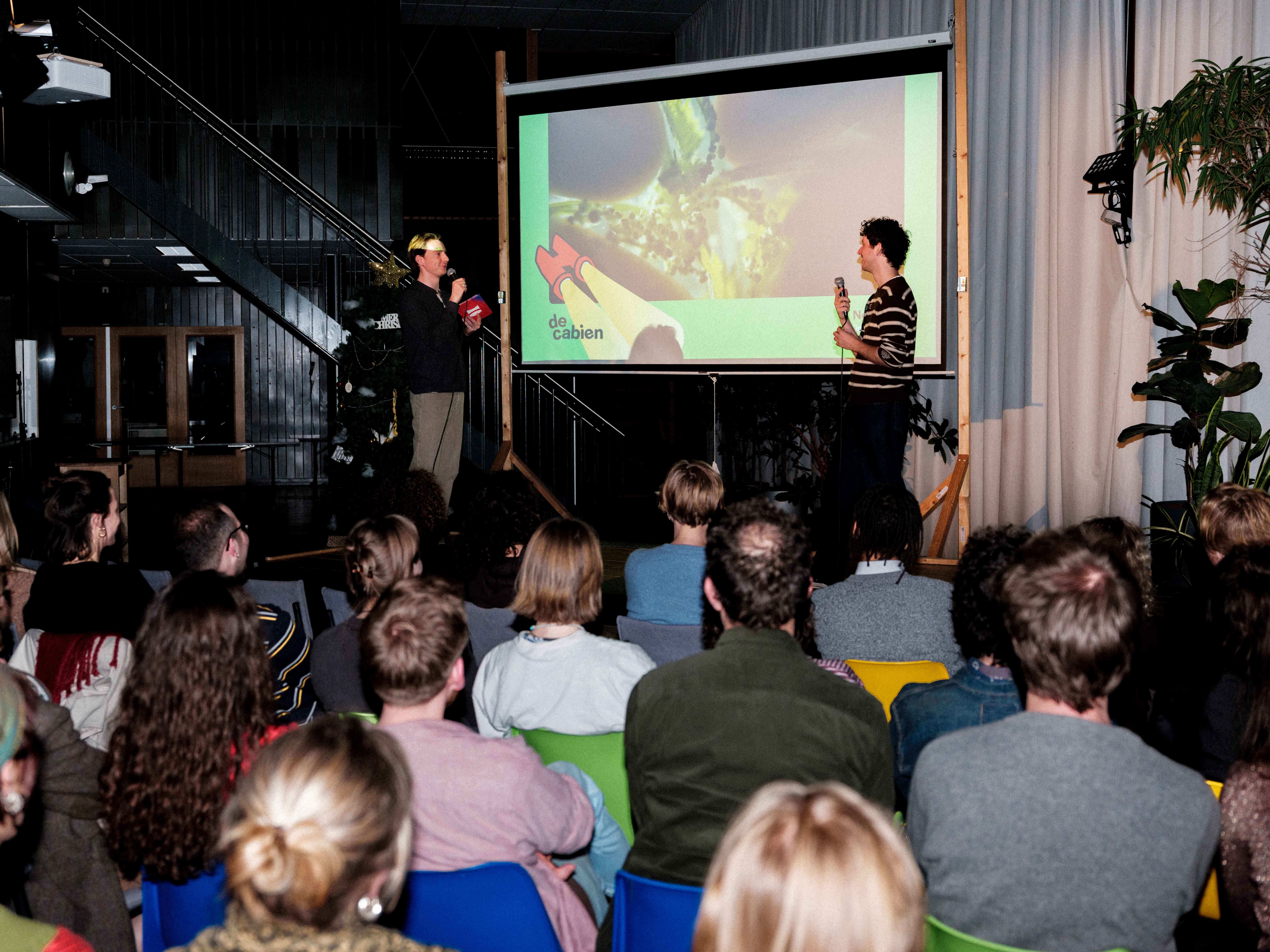 Er wordt een presentatie gegeven voor twee personen voor een groep mensen die in de zaal zitten