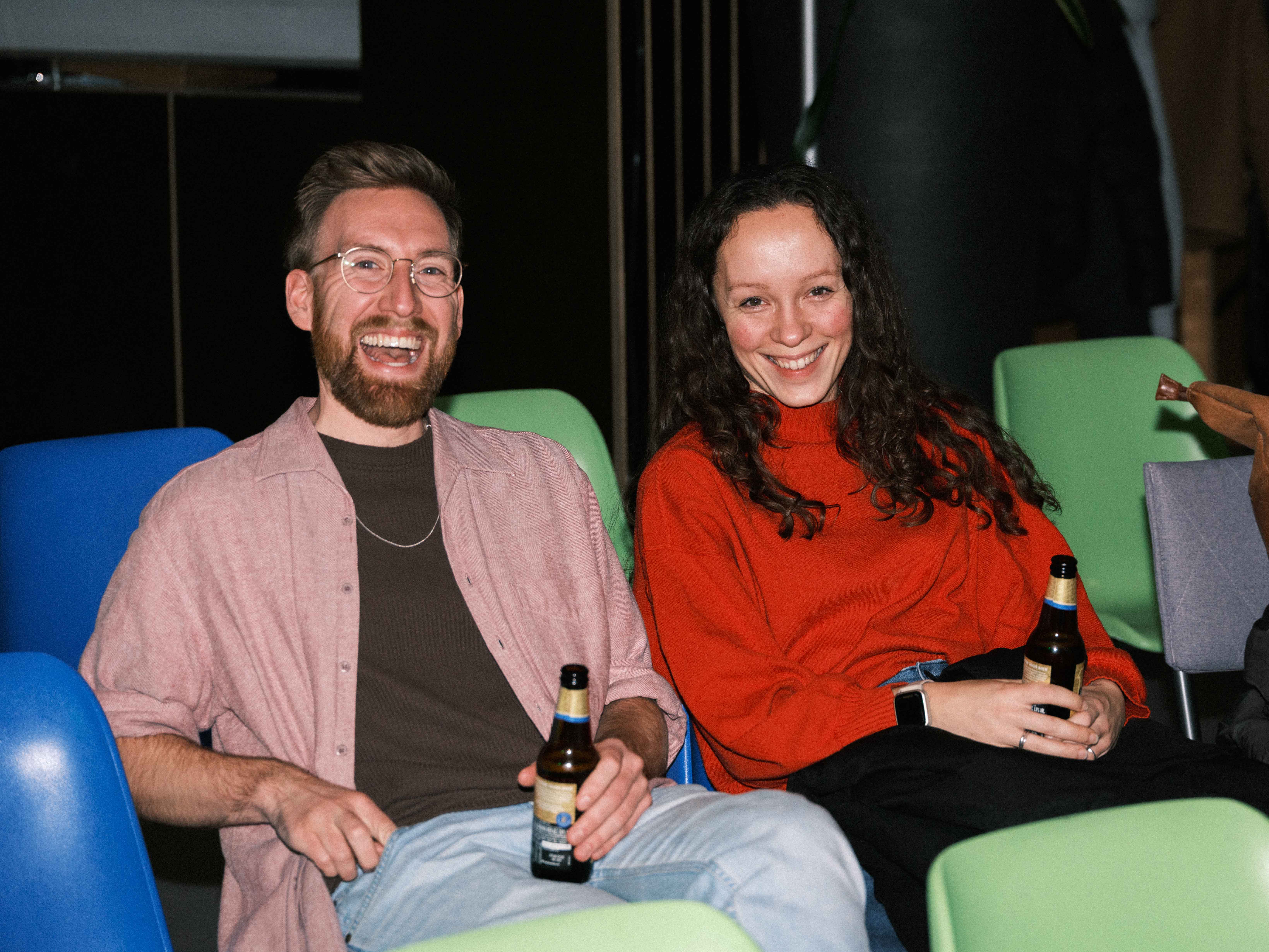 Twee mensen die gezellig op een bank zitten met een flesje bier.