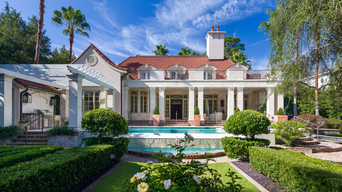 A design detail shot of wicker porch furniture with coastal throw pillows and a tray of sun-bleached seashells