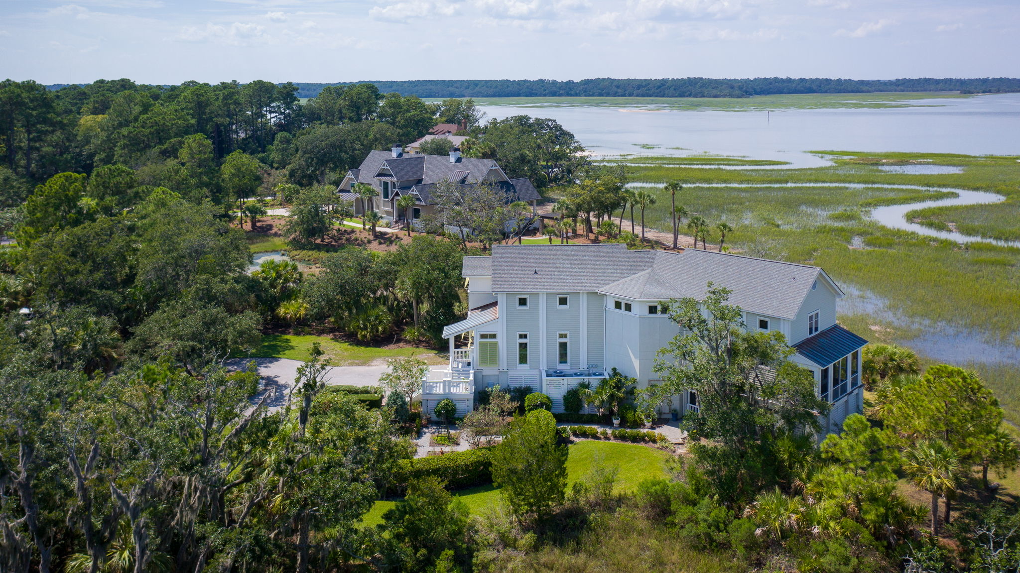 A design detail shot of wicker porch furniture with coastal throw pillows and a tray of sun-bleached seashells