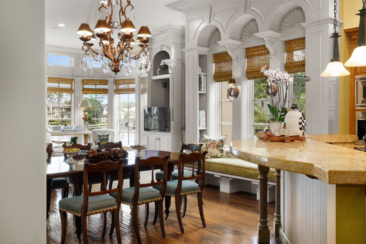 A design detail shot of wicker porch furniture with coastal throw pillows and a tray of sun-bleached seashells