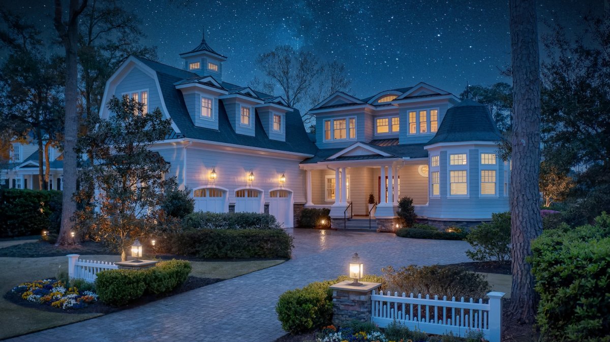 A design detail shot of wicker porch furniture with coastal throw pillows and a tray of sun-bleached seashells