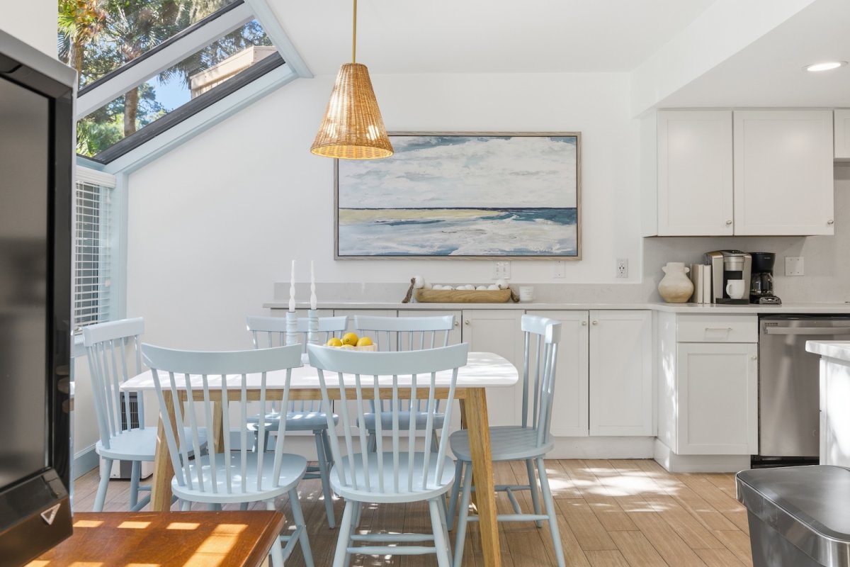 A design detail shot of wicker porch furniture with coastal throw pillows and a tray of sun-bleached seashells