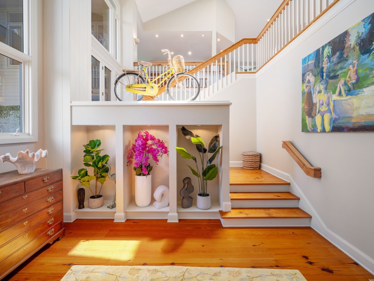 A design detail shot of wicker porch furniture with coastal throw pillows and a tray of sun-bleached seashells