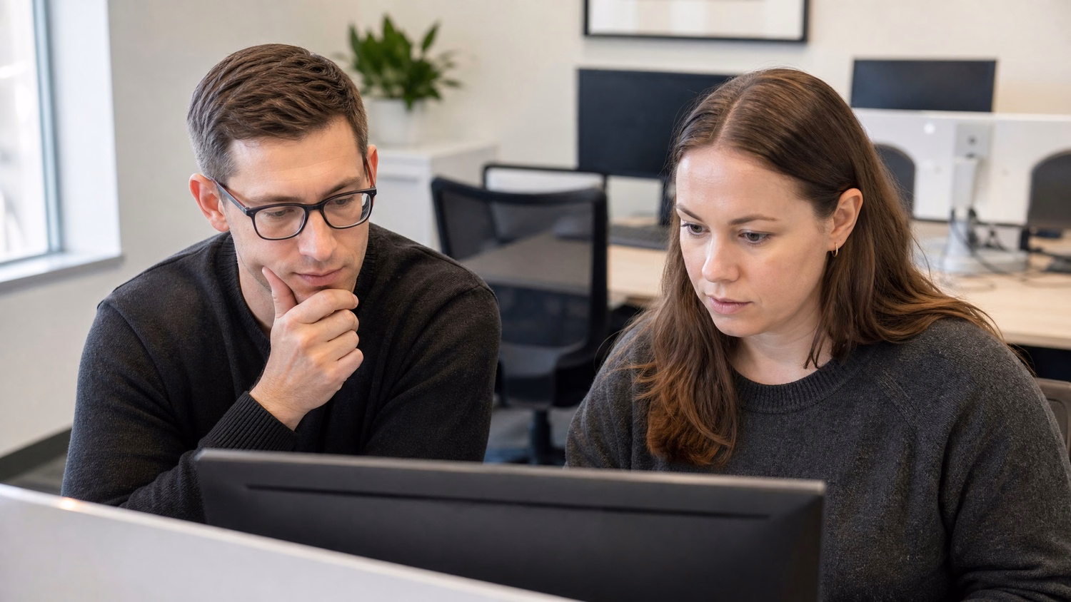 SIDE-BY-SIDE PAIR An IT professional two people seated side by side reviewin