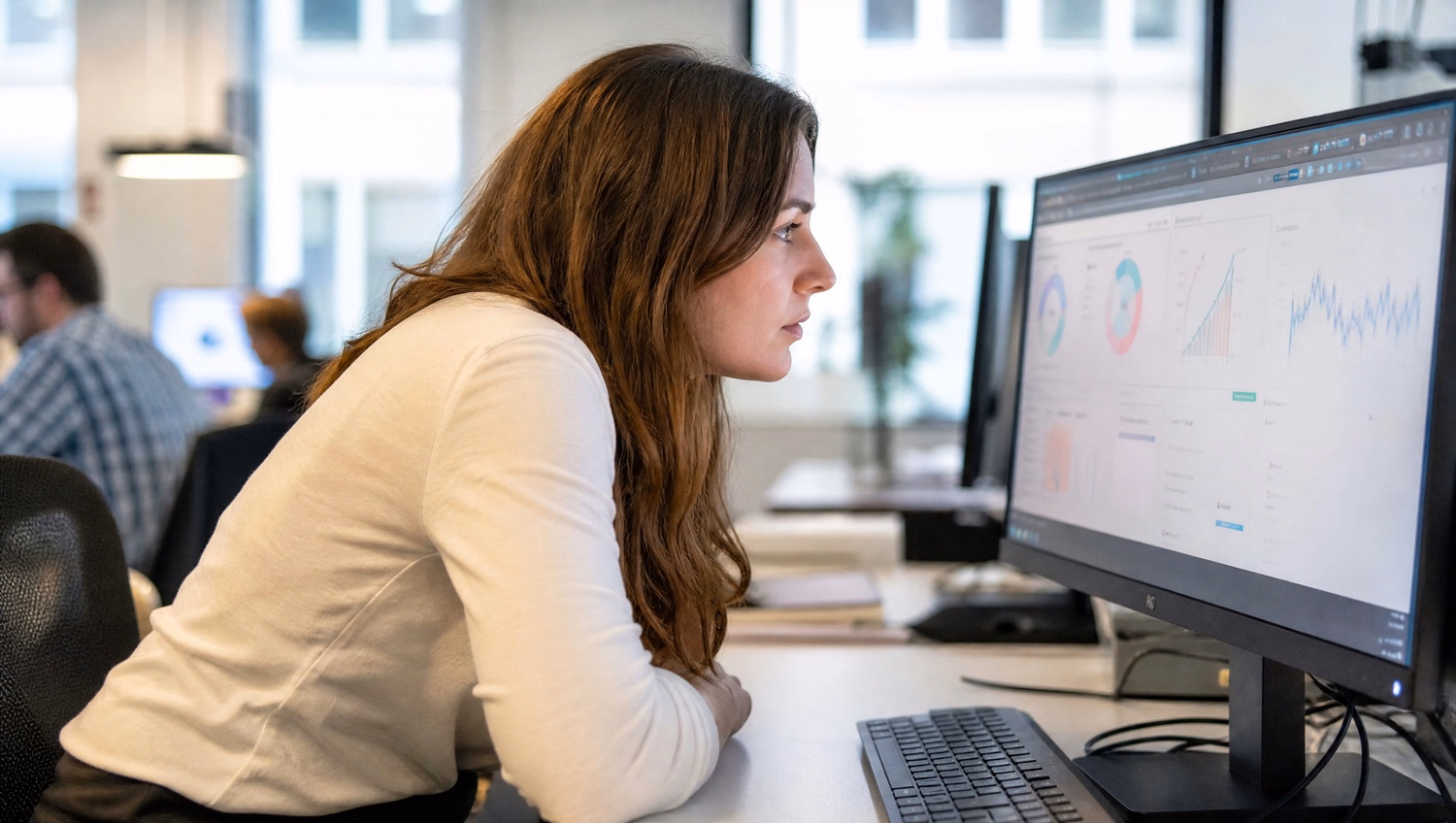 Woman intently studying computer screen at desk, CMMC compliance