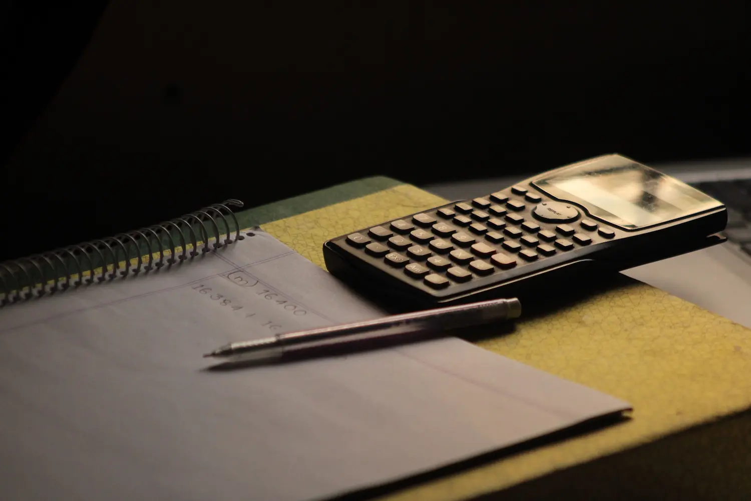 Gros plan sur une calculatrice et un cahier sur un bureau. Idéal pour illustrer des thèmes liés à l'éducation