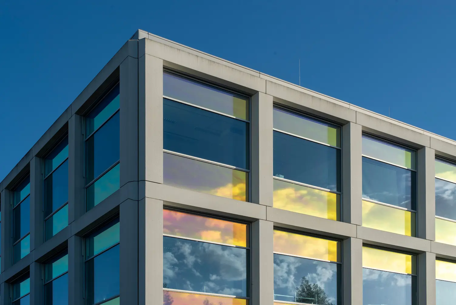 Façade d'un bâtiment avec du verre réfléchissant contre un ciel bleu