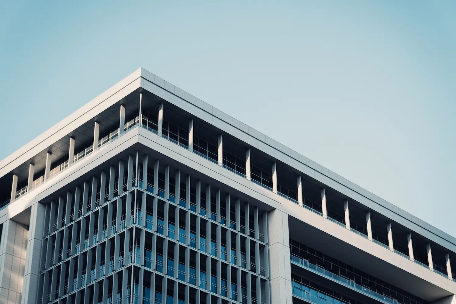 Immeuble de bureaux contemporain avec une façade en verre futuriste reflétant le ciel.