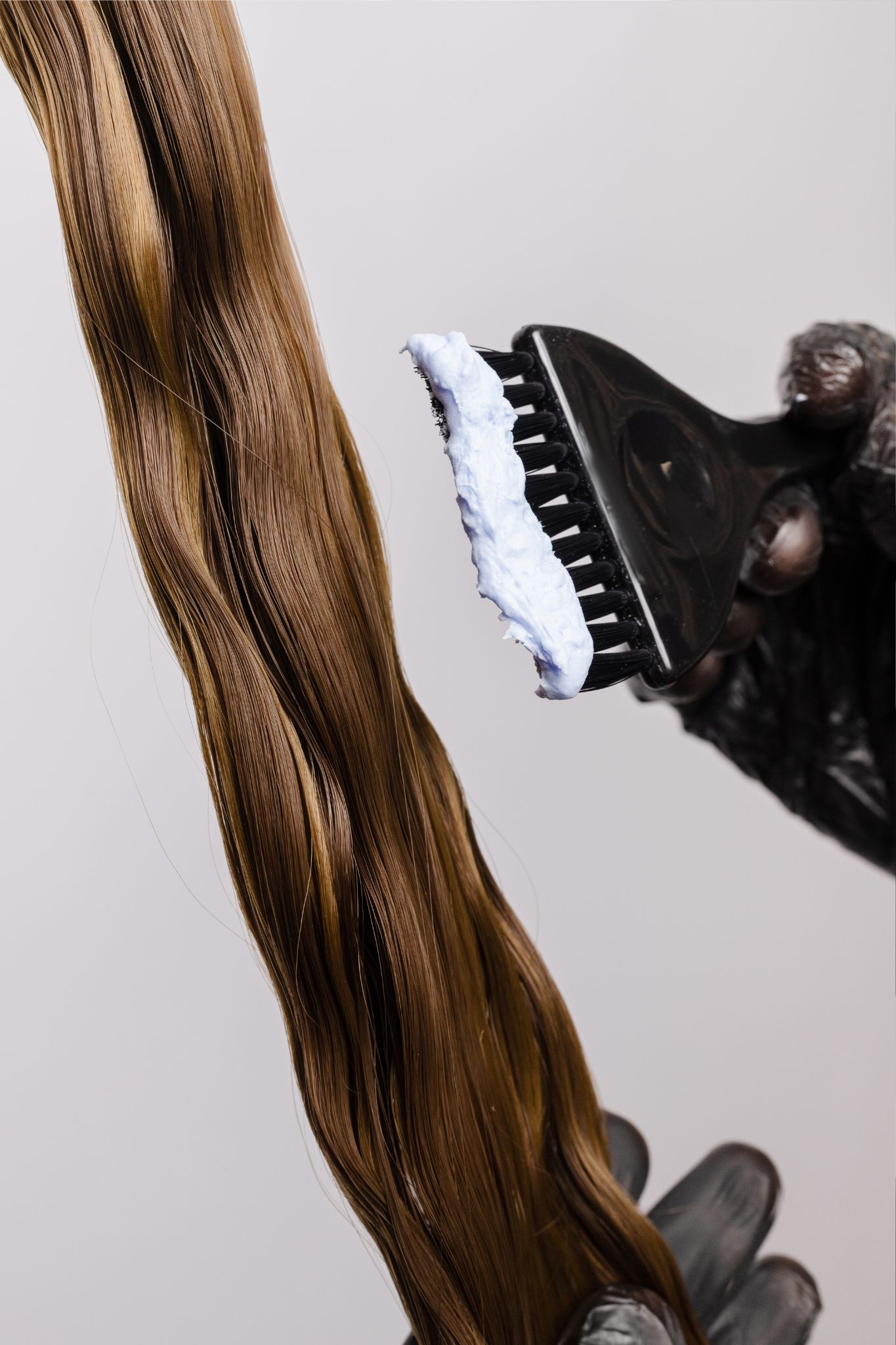 Pennello da parrucchiera con tinta su capelli biondi.