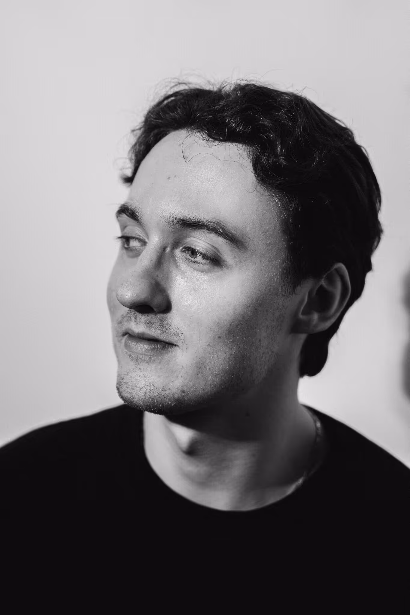 Black and white portrait of a young man with short curly hair looking to the side.