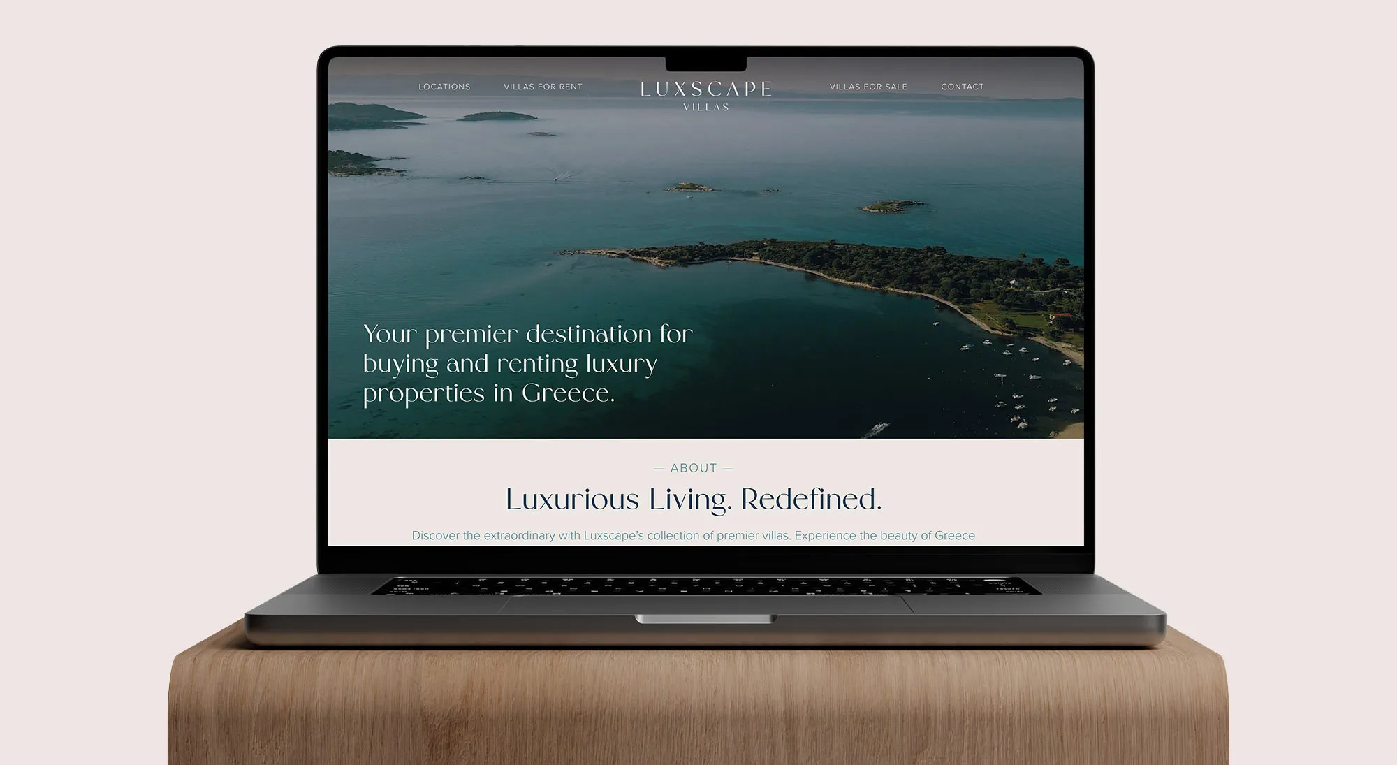 Laptop displaying Luxscape Villas website featuring a coastal aerial view with text promoting luxury properties in Greece.
