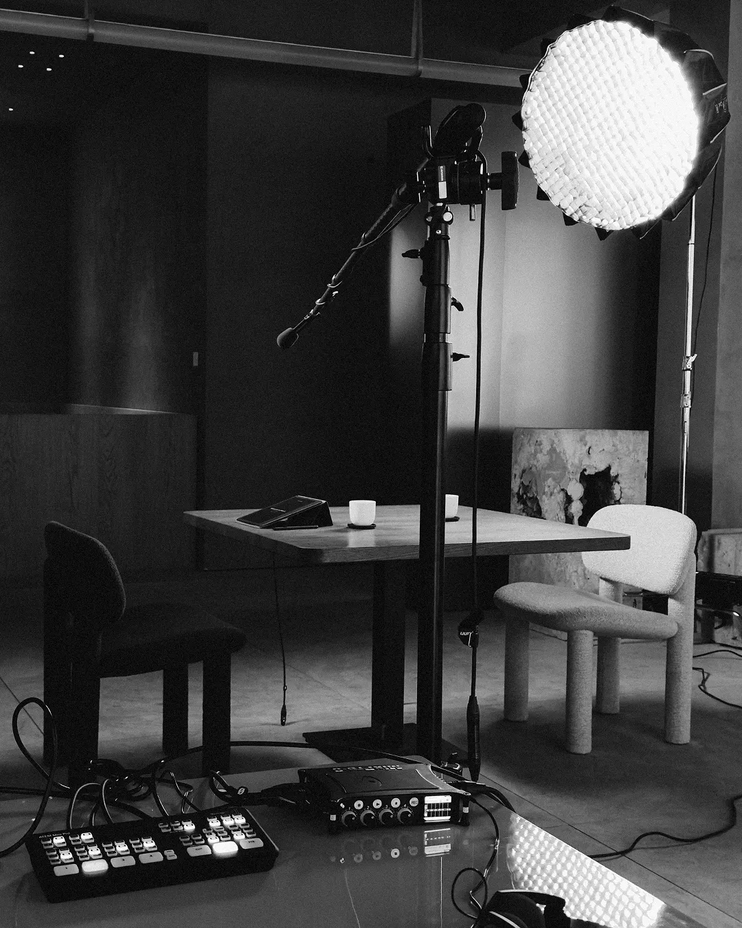 Black and white photo of a podcast recording setup with a microphone, large softbox light