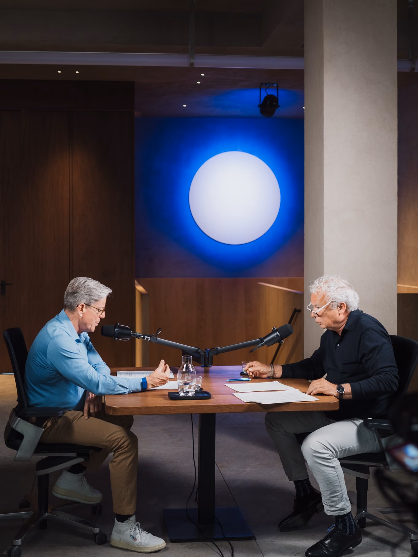 Two hosts recording an episode of the Umdenken podcast at a table with microphones