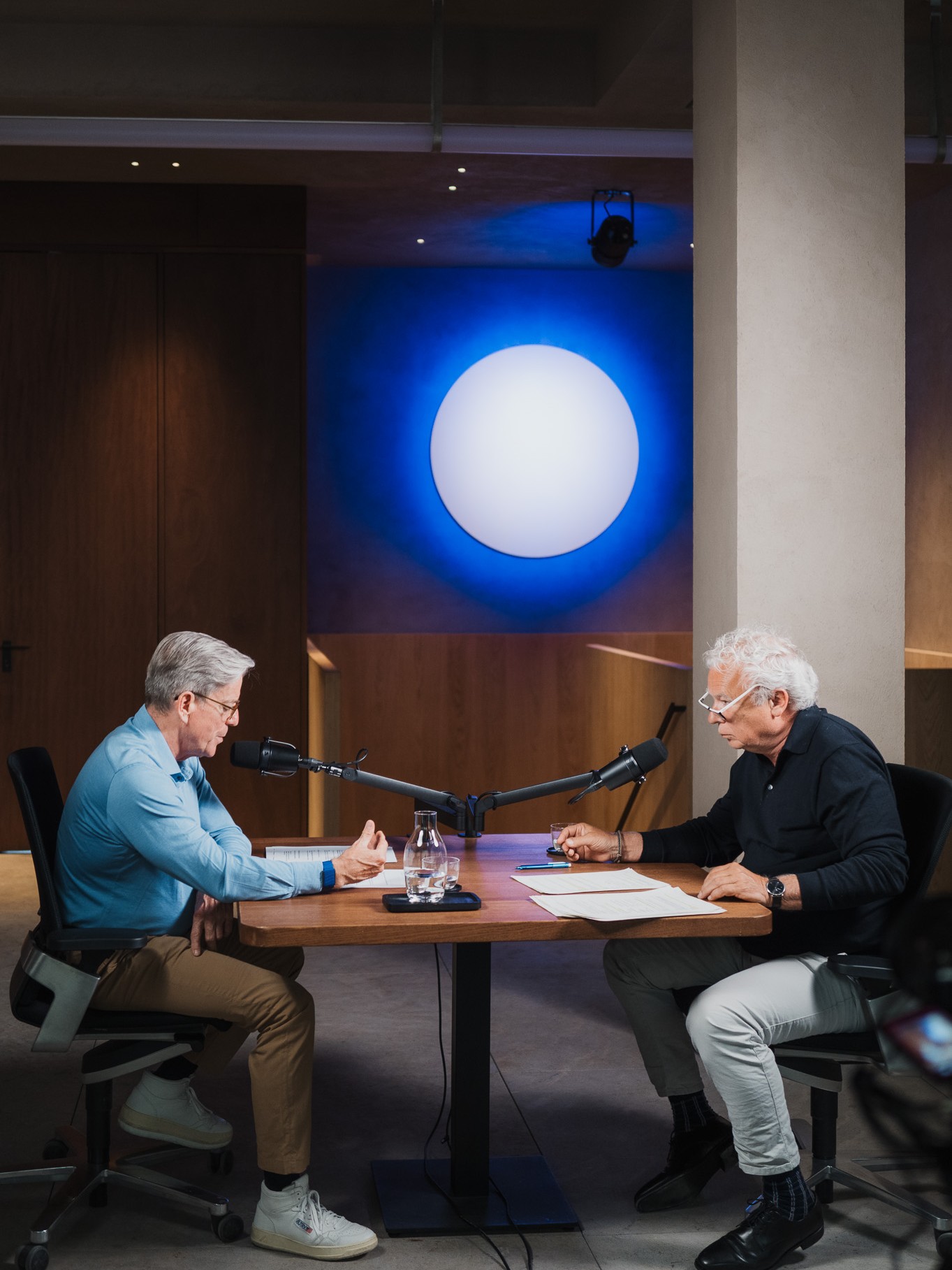 Two hosts recording an episode of the Umdenken podcast at a table with microphones