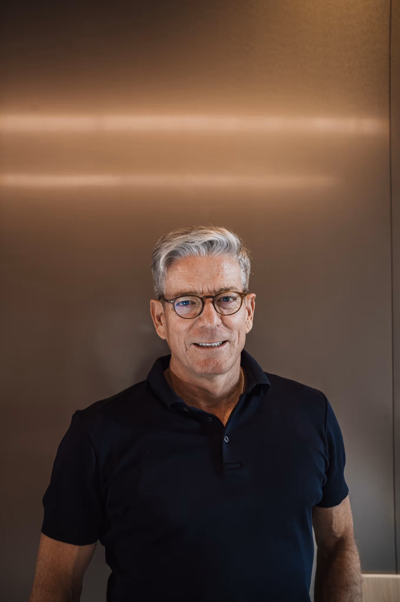 Gast im schwarzen Polo vor Metallwand – Business Podcast Interview München