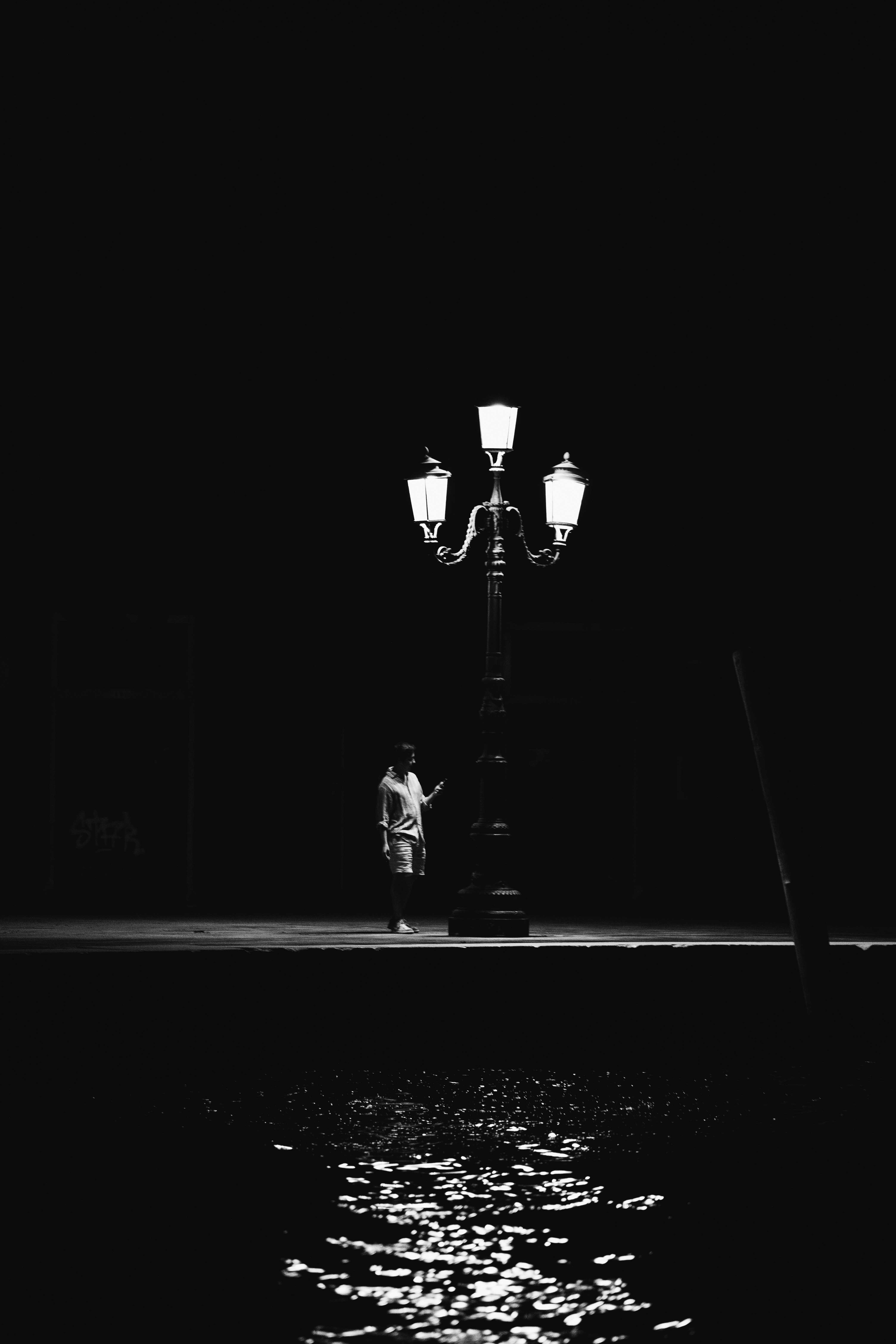 Venice in the Shadows by FADETOBLACK, fine art street photography, image 10: High-contrast black and white night scenes in Venice: a lone man walking across a dark square past an ornate