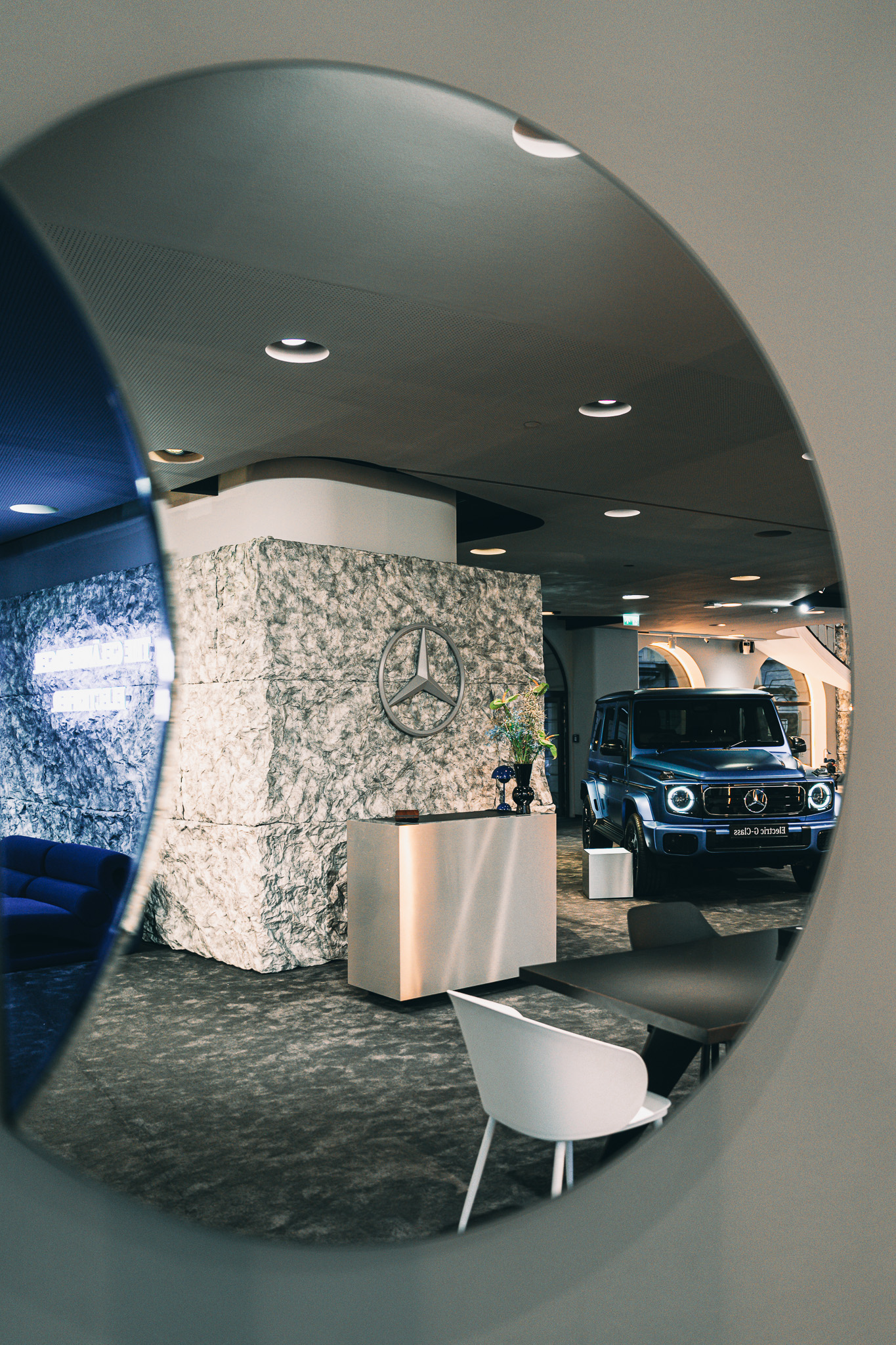 Blue Mercedes G-Class parked in a showroom beside a stone-textured wall with a Mercedes star emblem. Event photography by FADETOBLACK
