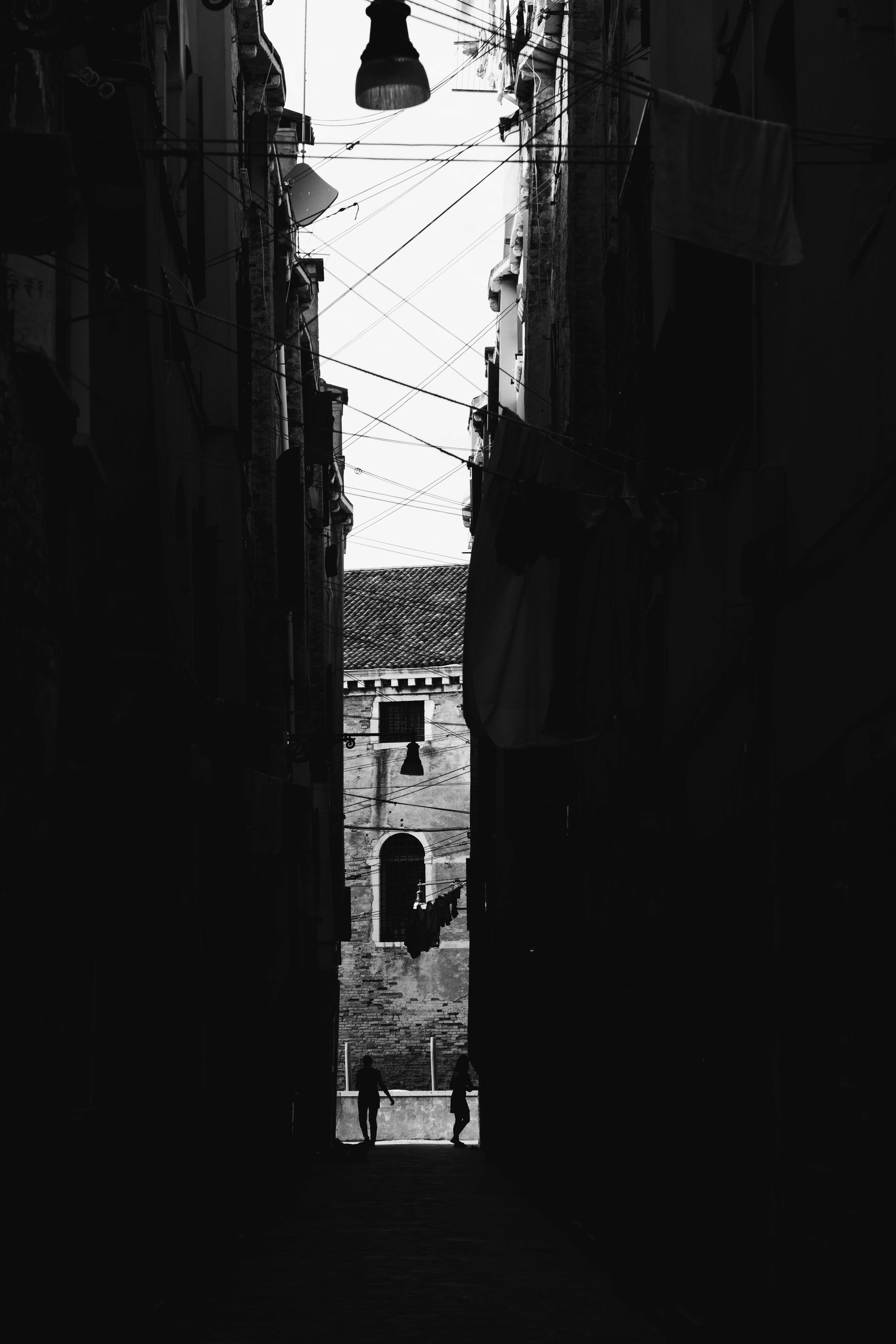 Venice in the Shadows by FADETOBLACK, fine art street photography, image 16: High-contrast black and white night scenes in Venice: a lone man walking across a dark square past an ornate