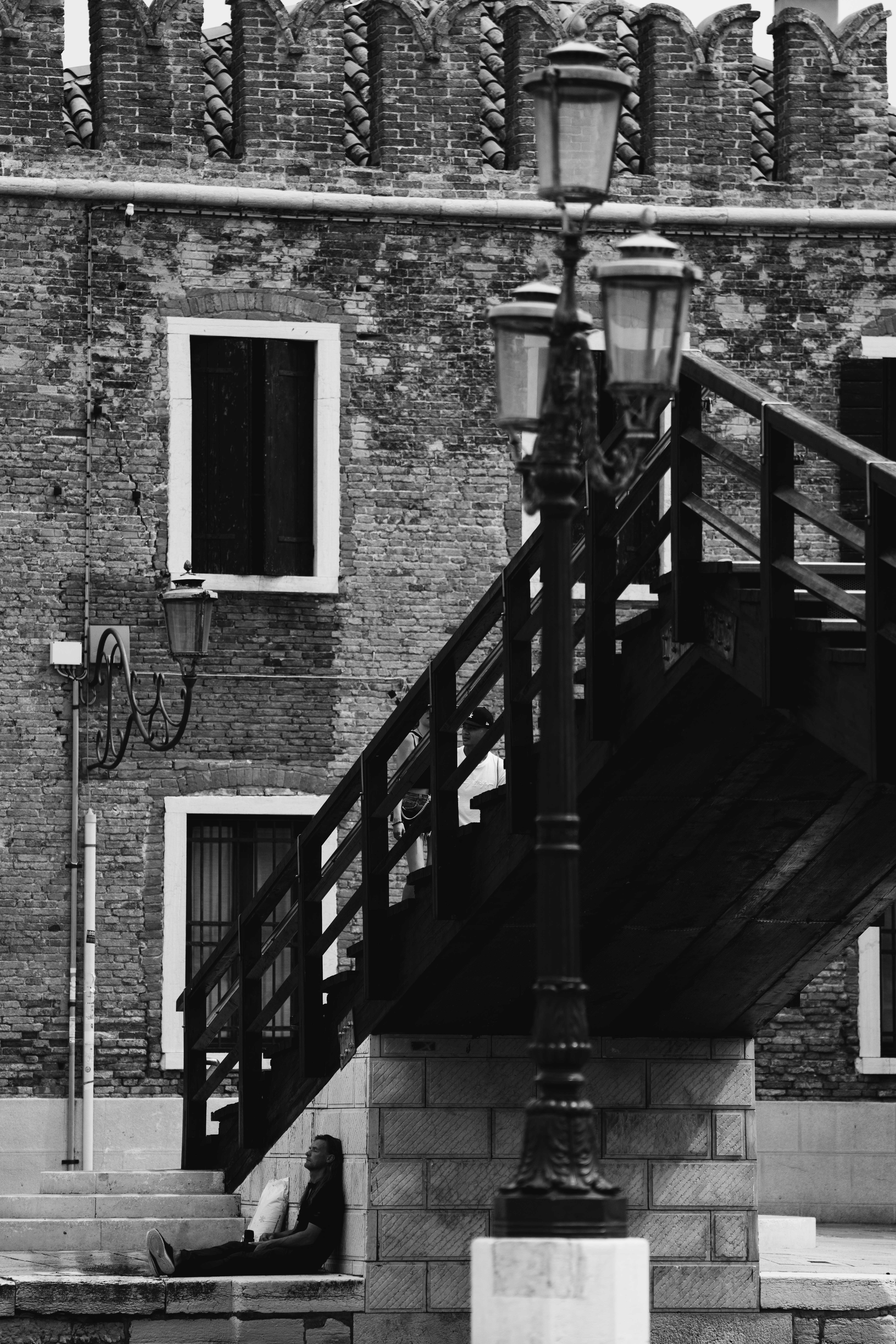 Venice in the Shadows by FADETOBLACK, fine art street photography, image 19: High-contrast black and white night scenes in Venice: a lone man walking across a dark square past an ornate