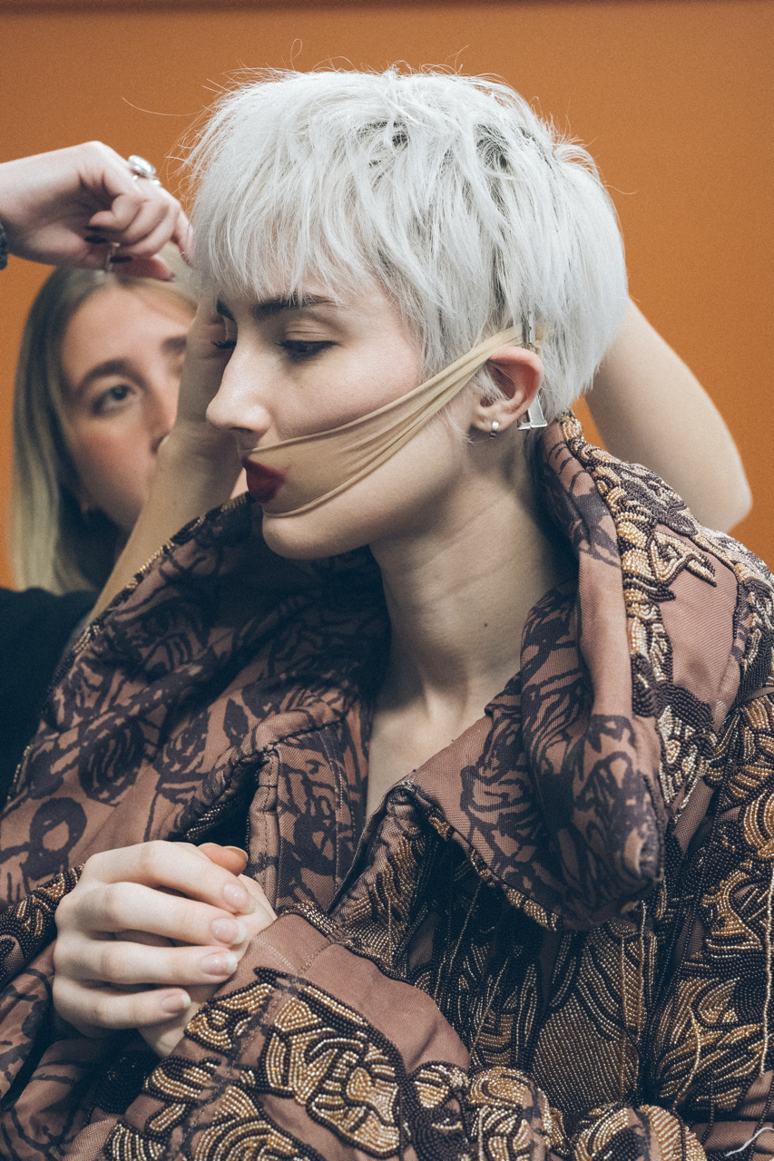 Jaang by FADETOBLACK, editorial fashion photography, image 22: Studio fashion editorial of a model with short platinum hair wearing avant-garde statement pieces, including