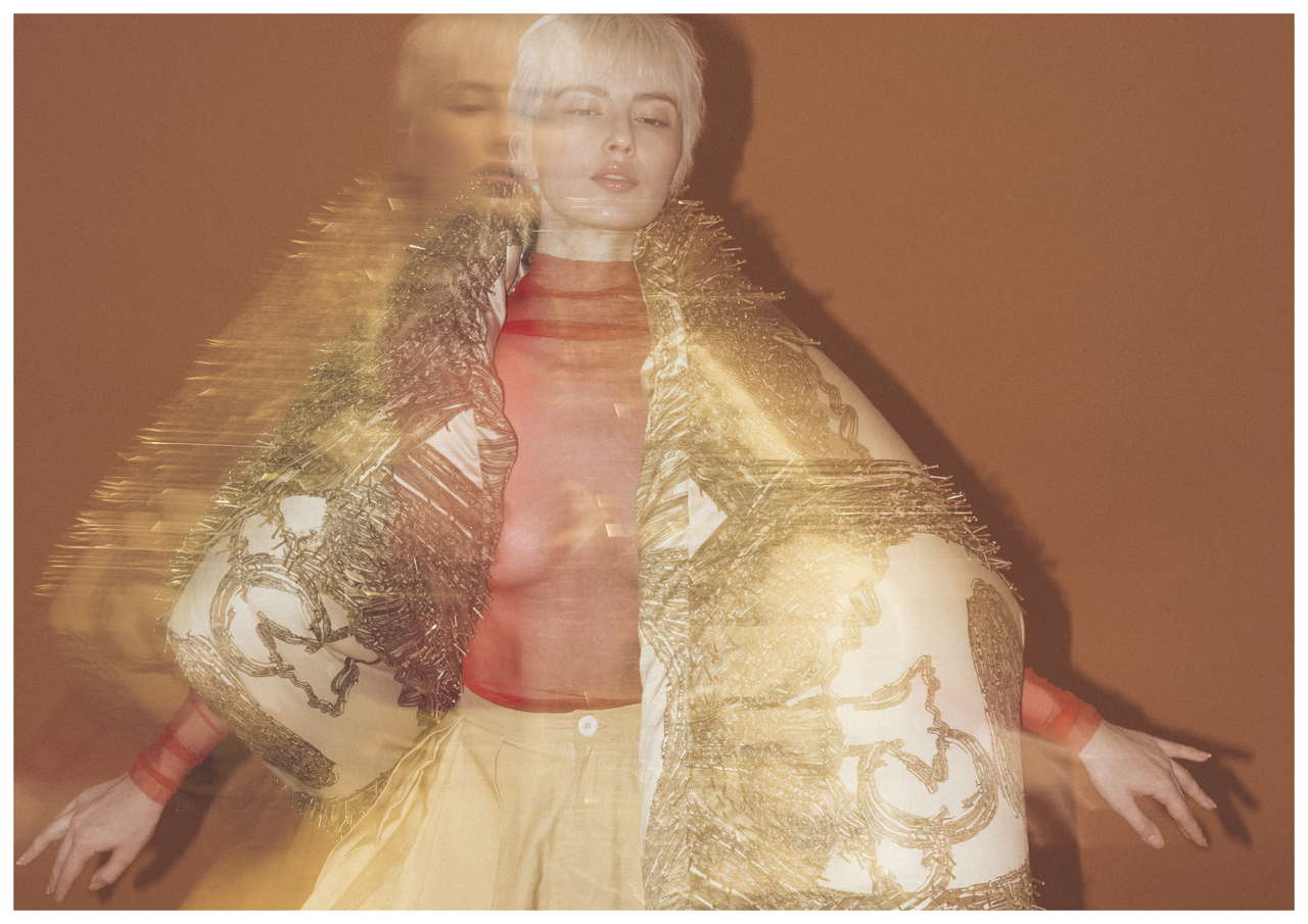 Jaang by FADETOBLACK, editorial fashion photography, image 29: Studio fashion editorial of a model with short platinum hair wearing avant-garde statement pieces, including