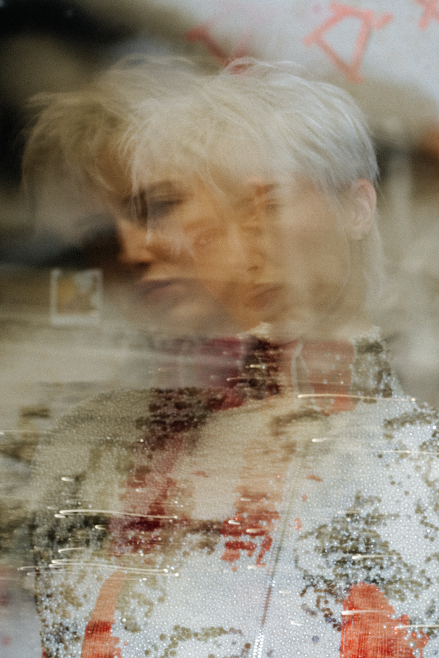 Jaang by FADETOBLACK, editorial fashion photography, image 25: Studio fashion editorial of a model with short platinum hair wearing avant-garde statement pieces, including