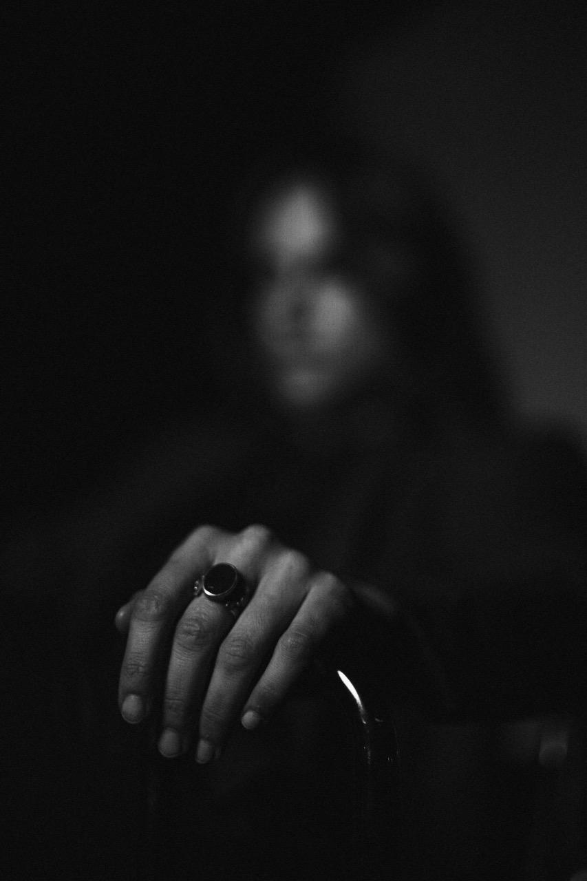 Hanna: The Transformation by FADETOBLACK, fine art portrait photography, image 18: Low-key black and white studio portrait series of a woman in a dark suit posing on and around a chrome-framed
