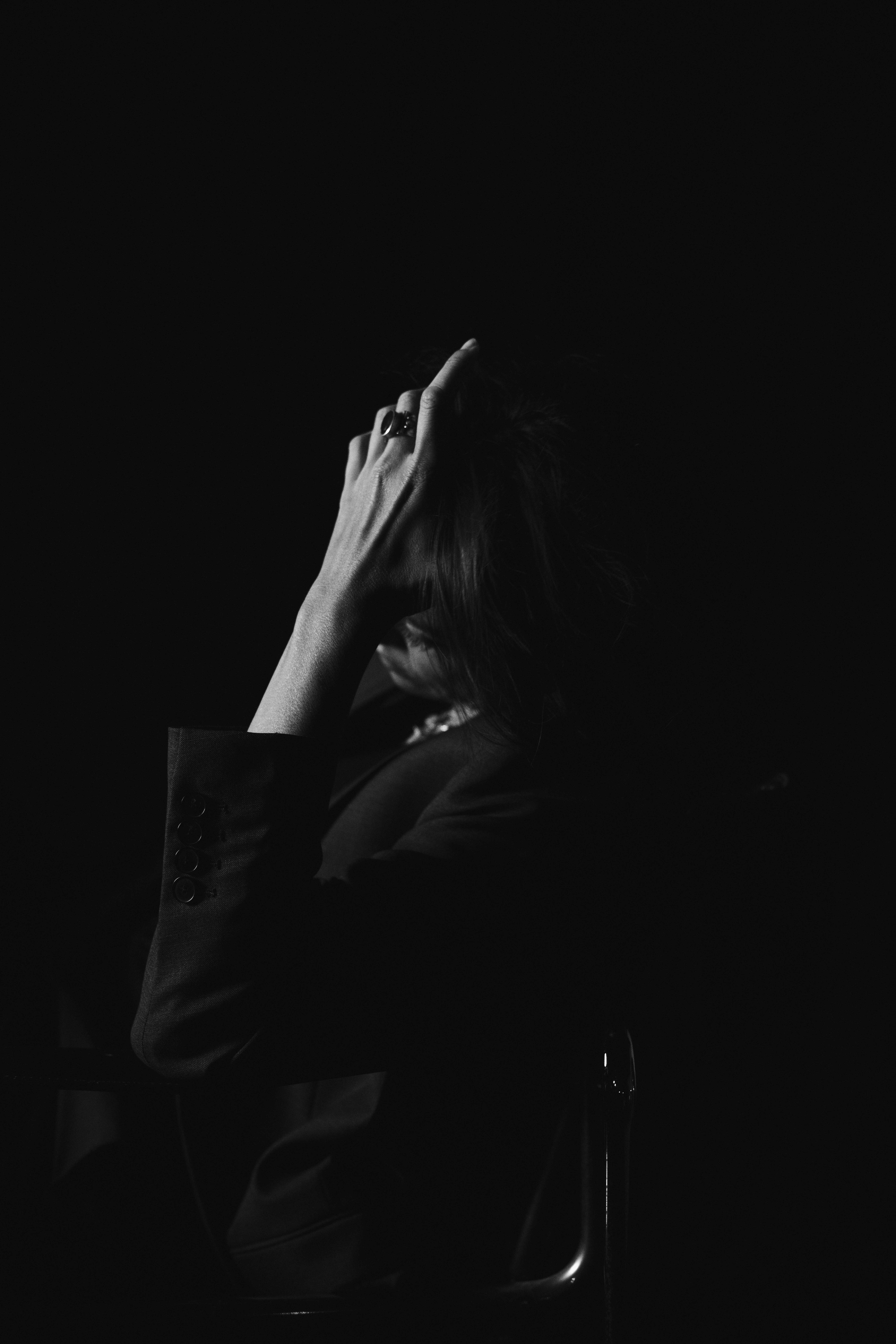 Hanna: The Transformation by FADETOBLACK, fine art portrait photography, image 11: Low-key black and white studio portrait series of a woman in a dark suit posing on and around a chrome-framed