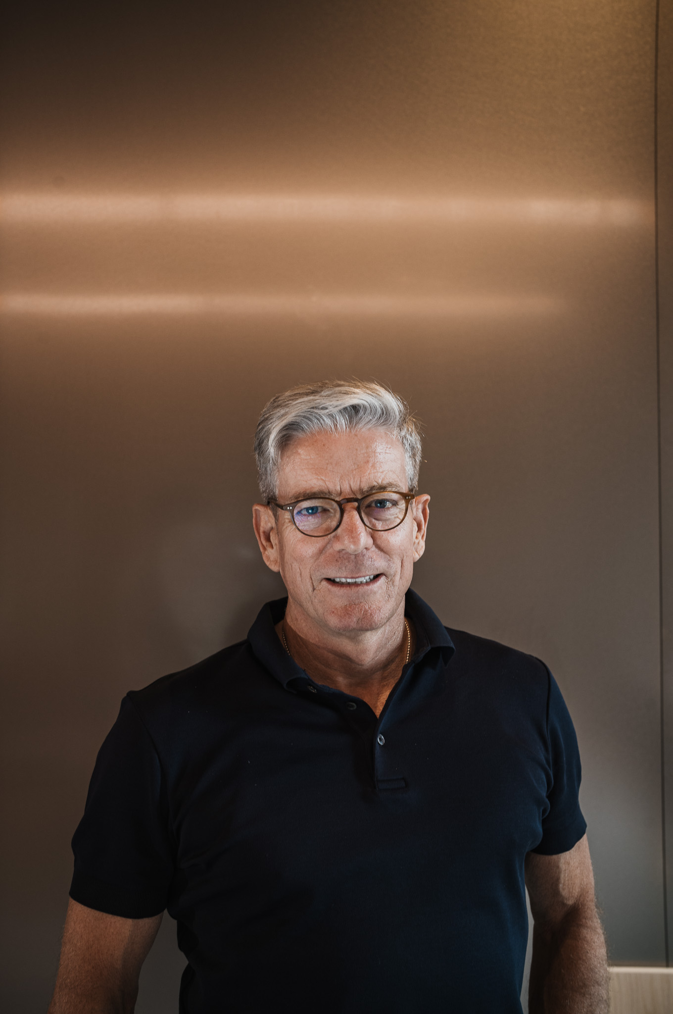 Gast im schwarzen Polo vor Metallwand, Business Podcast Interview München