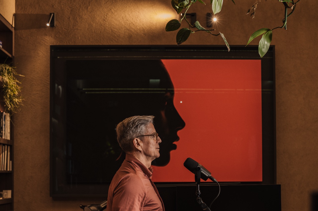 Sideview host vor roter Kunstwand, Kreativpodcast München