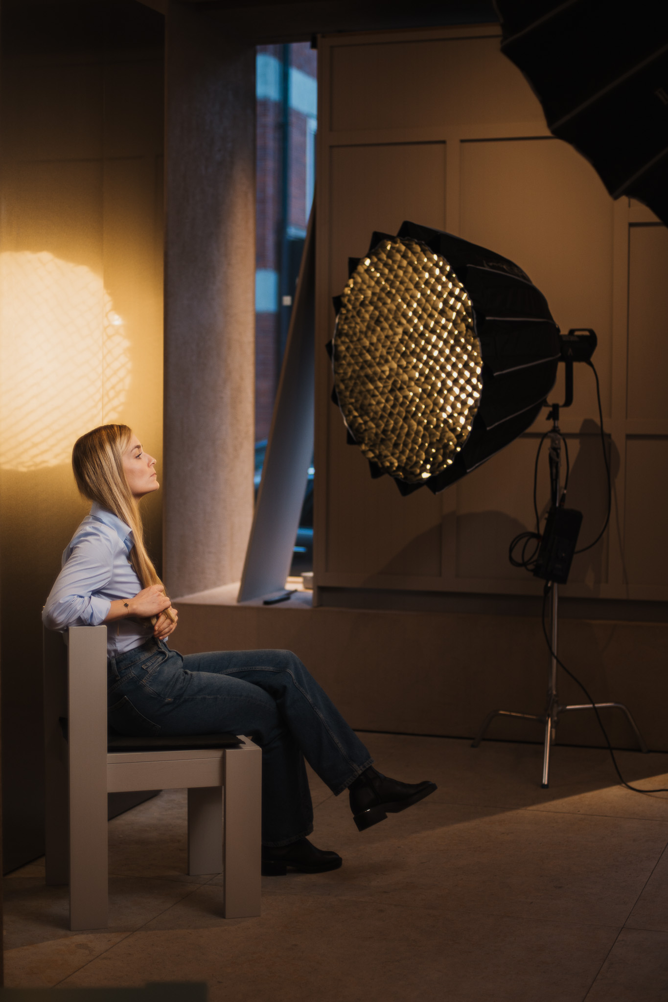 Gästin sitzt entspannt unter Parabollicht, Behind-the-Scenes Podcast Videodreh München