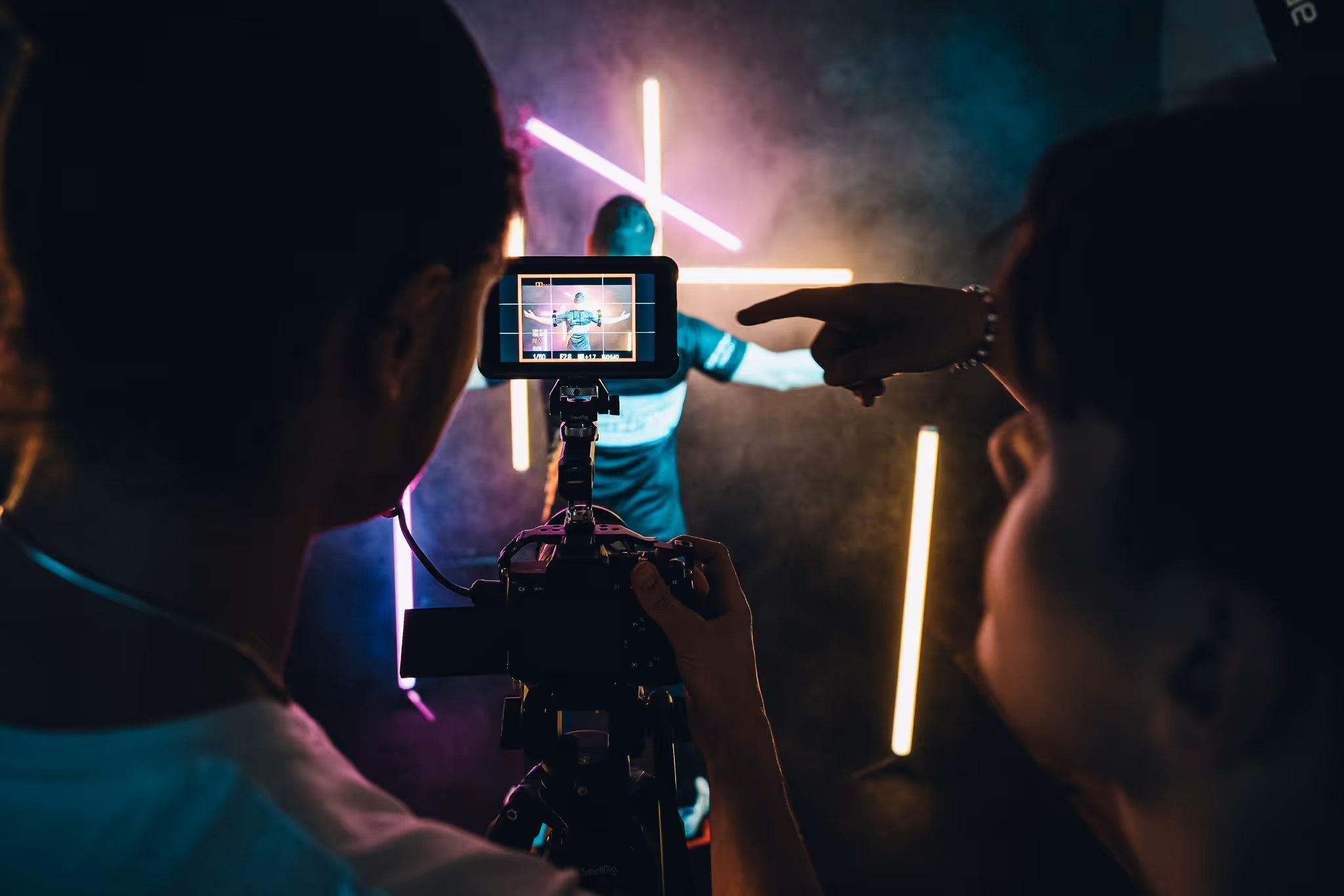 Camera filming a person in front of coloured neon light during a video production, FADETOBLACK Munich