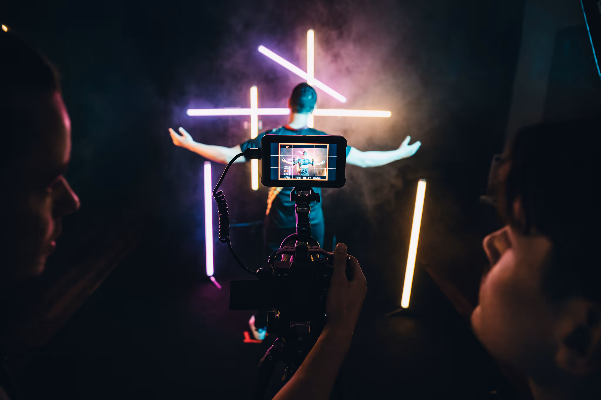 Person with outstretched arms in front of neon lights being filmed, symbolic image for reel length, FADETOBLACK Munich