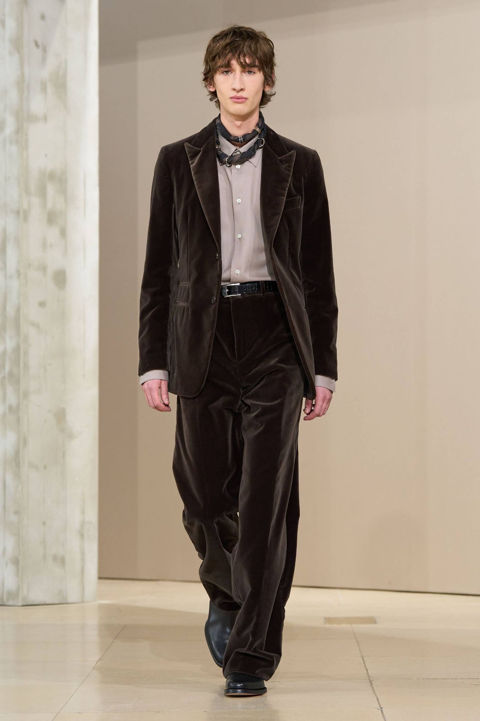 Modelo con traje de terciopelo caf oscuro pañuelo caf camisa gris topo y zapatos negros