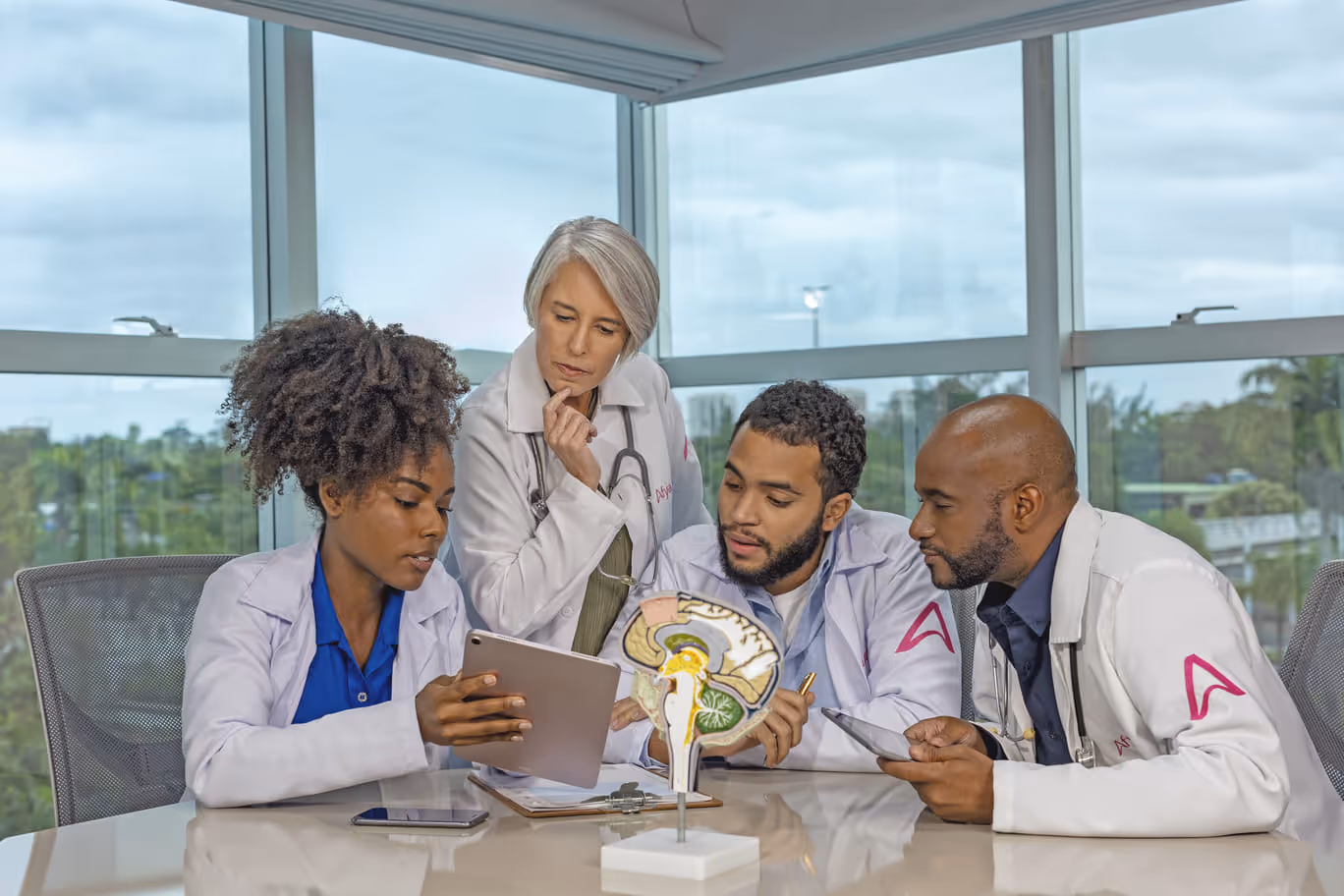 Três alunos analisando o material de estudos em um tablet com a ajuda da professora